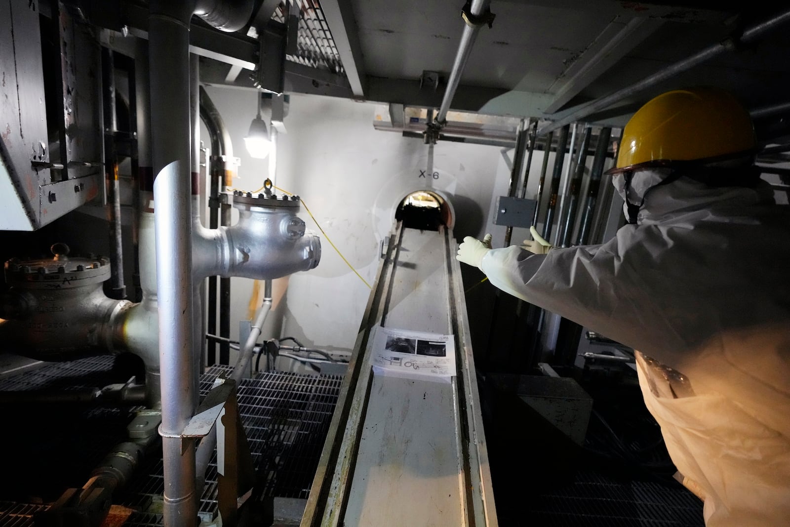 An employee of Tokyo Electric Power Company Holdings (TEPCO) speaks at the area under the Unit 5 reactor pressure vessel, which survived the earthquake-triggered tsunami in 2011, at the Fukushima Daiichi nuclear power plant in Futaba town, northeastern Japan, on Monday Feb. 20, 2025. (AP Photo/Eugene Hoshiko)