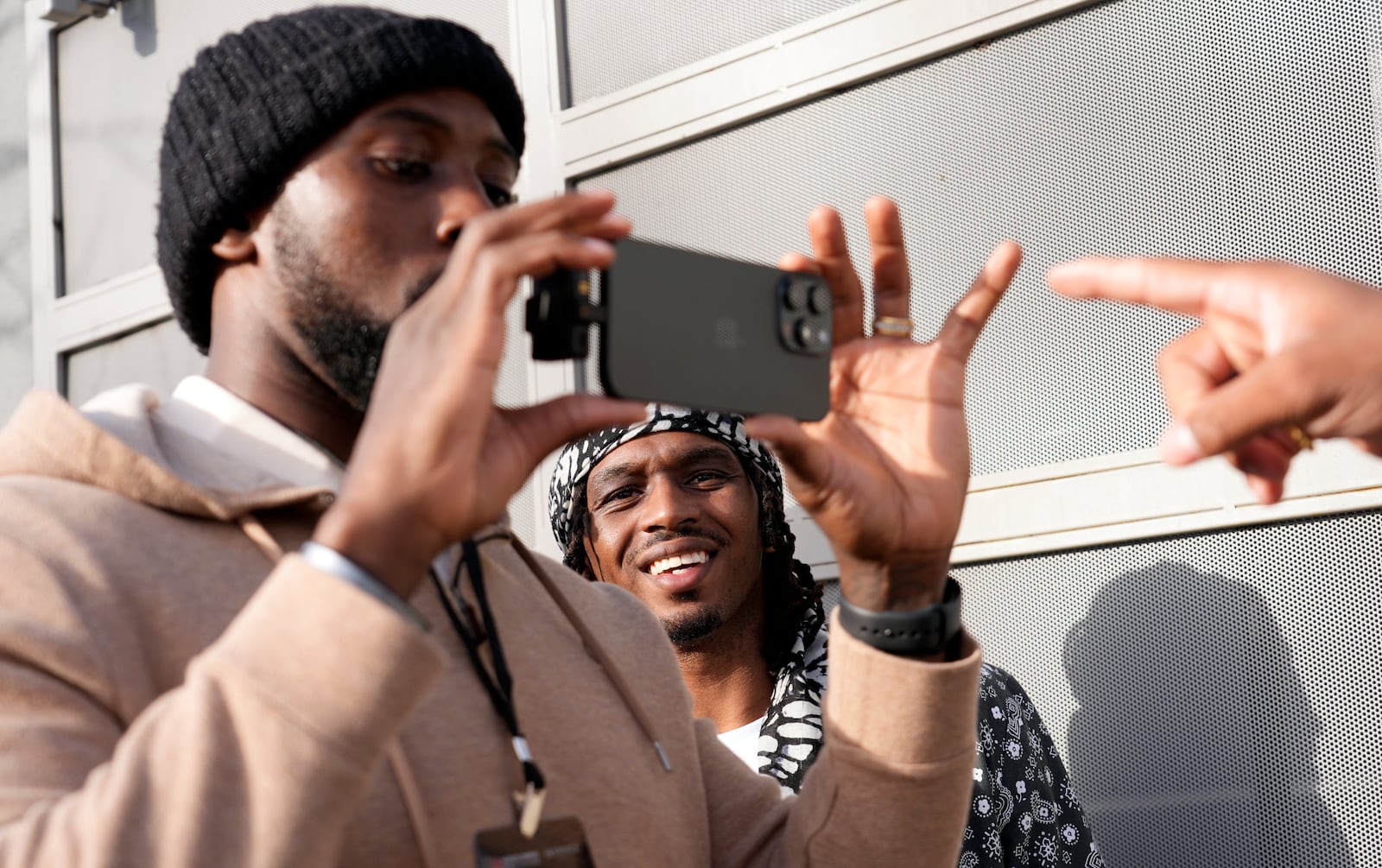 Retired NFL player T.J. Wright, center, watches footage on NFL player Charles Harris' phone as they film a scene from the film "Meet the Blacks" during a filmmaking workshop for NFL players on Tuesday, March 4, 2025, in Santa Monica, Calif. (AP Photo/Chris Pizzello)