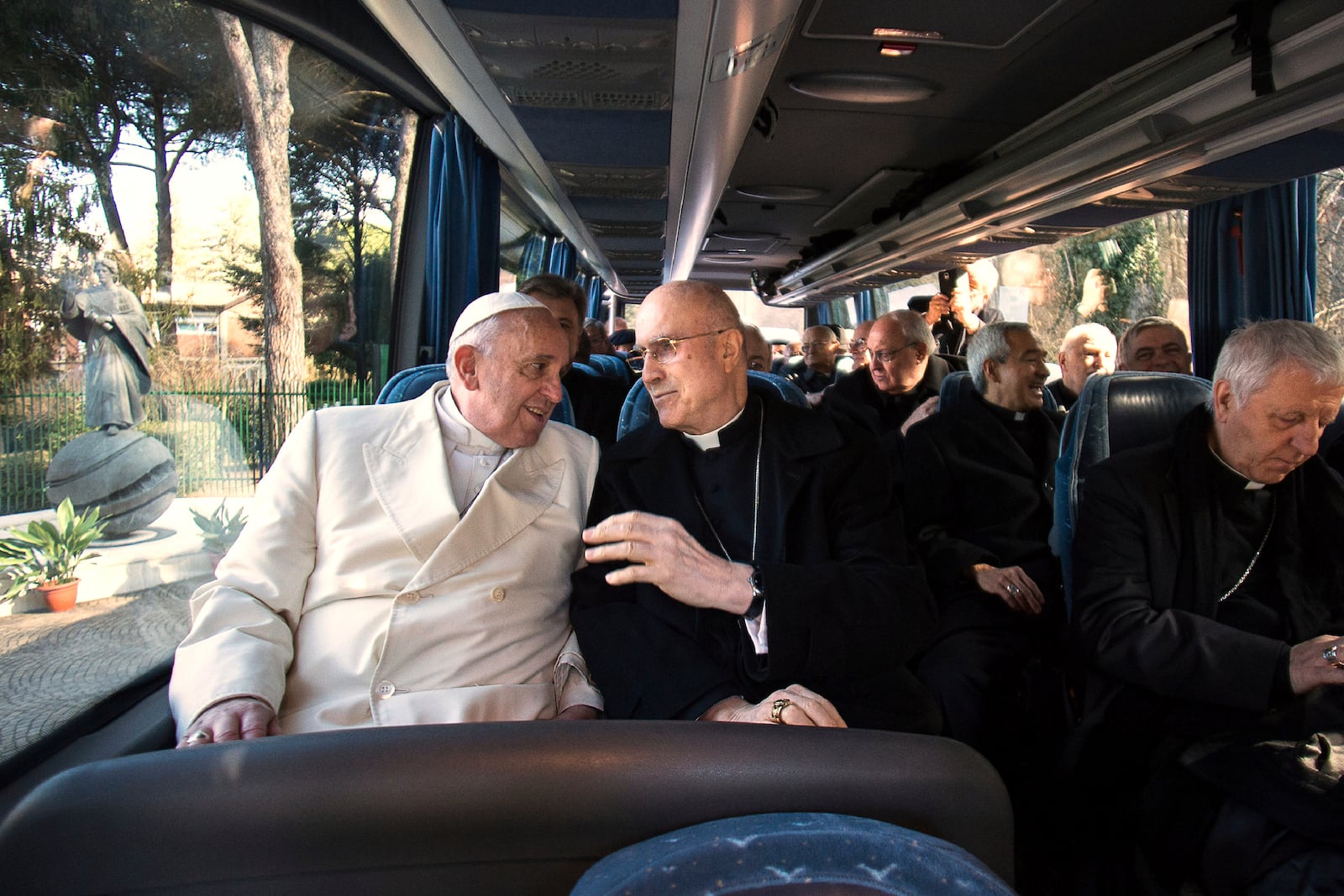 FILE - In this Feb. 27, 2015 file photo, Pope Francis, left, talks to Cardinal Tarciso Bertone as they sit on a bus at the end of a week of Lenten spiritual retreat in Ariccia, in the hills overlooking Rome. (AP Photo/L'Osservatore Romano, Pool)