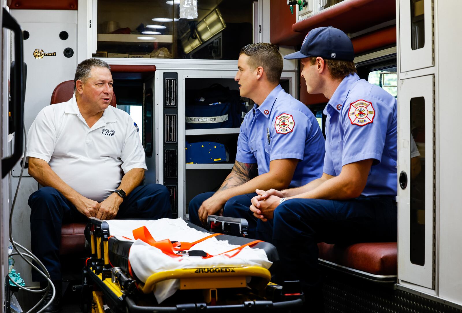 Middletown Division of Fire Chief Paul Lolli, left, sits with firefighter/paramedics Jacob Lentz, middle, and Josh Lentz, right, inside a medic unit at their headquarters Thursday, August 12, 2021 in Middletown. The Lentz brothers had a similar picture taken with Lolli when they were kids during a visit to the fire station. NICK GRAHAM / STAFF