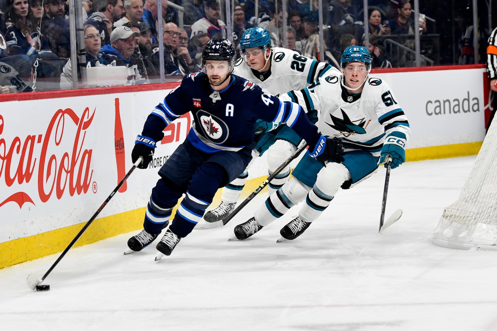 Winnipeg Jets' Josh Morrissey (44) carries the puck around San Jose Sharks' Jack Thompson (26) and Collin Graf (51) during the second period of an NHL hockey game in Winnipeg, Manitoba, Monday, Feb. 24, 2025. (Fred Greenslade/The Canadian Press via AP)