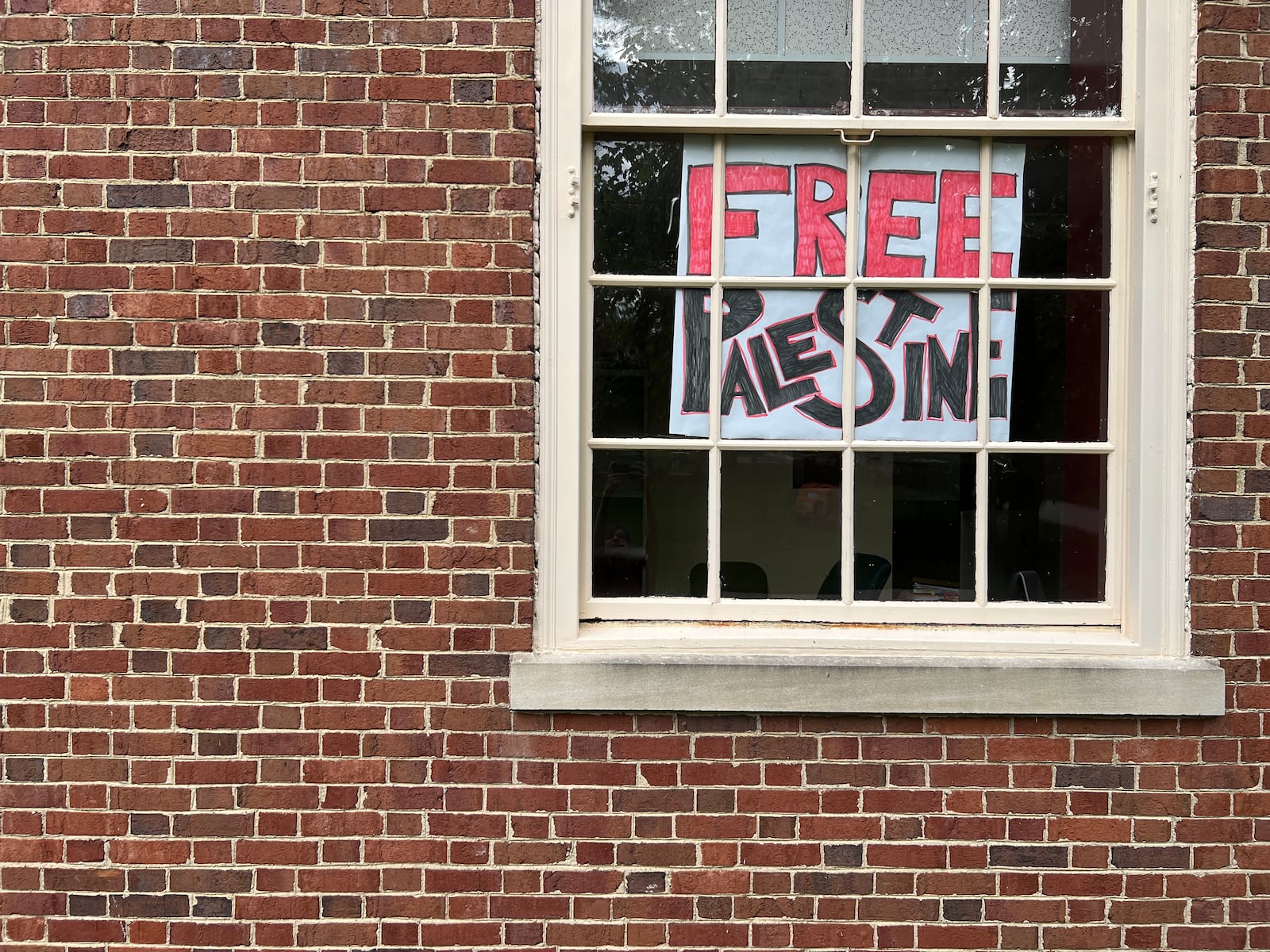 A sign in support of Palestinians hangs in a window on Miami University's Oxford campus. A pro-Palestinian encampment started by the Miami University chapter of Students for Justice in Palestine entered its second night Friday, May 3, 2024, on the academic quad outside Roudebush Hall, the university’s main administrative building. SEAN SCOTT/CONTRIBUTED