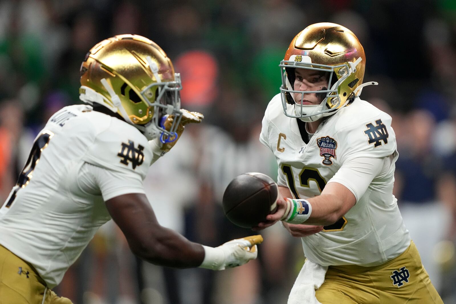 Notre Dame quarterback Riley Leonard hands the ball off to running back Jeremiyah Love, left, during the first half against Georgia in the quarterfinals of a College Football Playoff, Thursday, Jan. 2, 2025, in New Orleans. (AP Photo/Gerald Herbert)