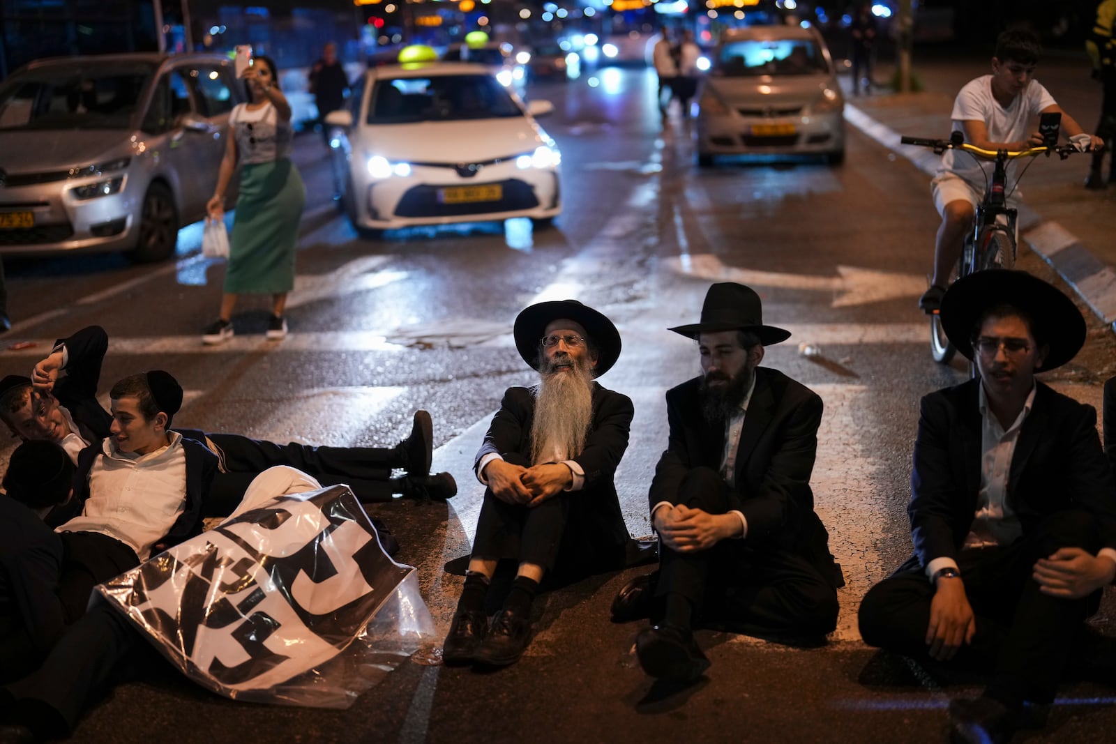 Ultra-Orthodox Jewish men block a road during a protest against army recruitment in Bnei Brak, near Tel Aviv, Israel, Sunday, Nov. 17, 2024. (AP Photo/Francisco Seco)