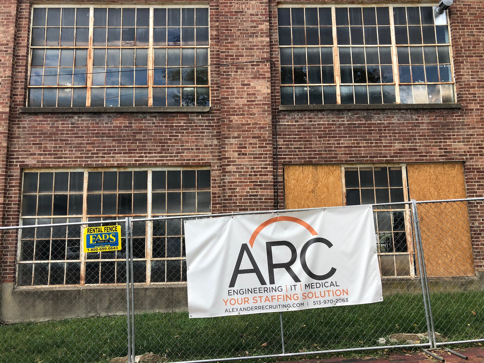 A sign for Alexander Recruiting hangs from a security fence around a former shoe factory the family has proposed for a  $12 million redevelopment.