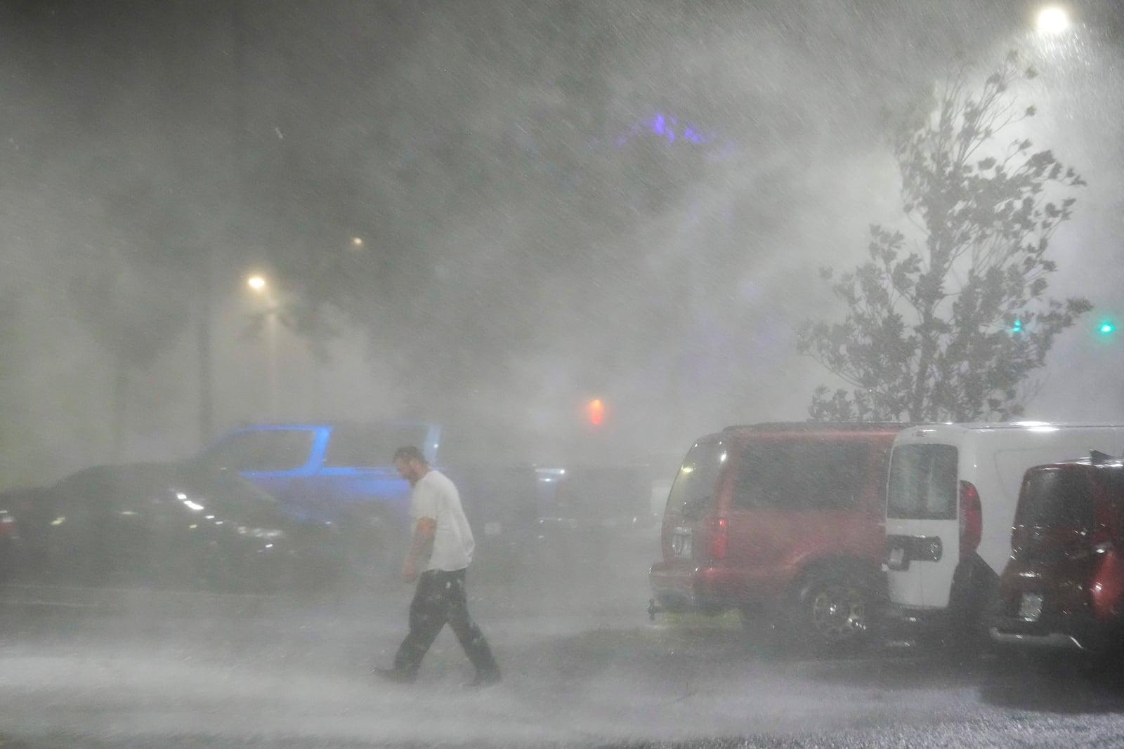 Max Watts, of Buford, Ga., walks in the parking lot to check on a trailer parked outside the hotel where he is riding out Hurricane Milton with coworkers, Wednesday, Oct. 9, 2024, in Tampa, Fla. Watts, who works for a towing company, was deployed with colleagues to Florida to aid in the aftermath of the storm. (AP Photo/Julio Cortez)