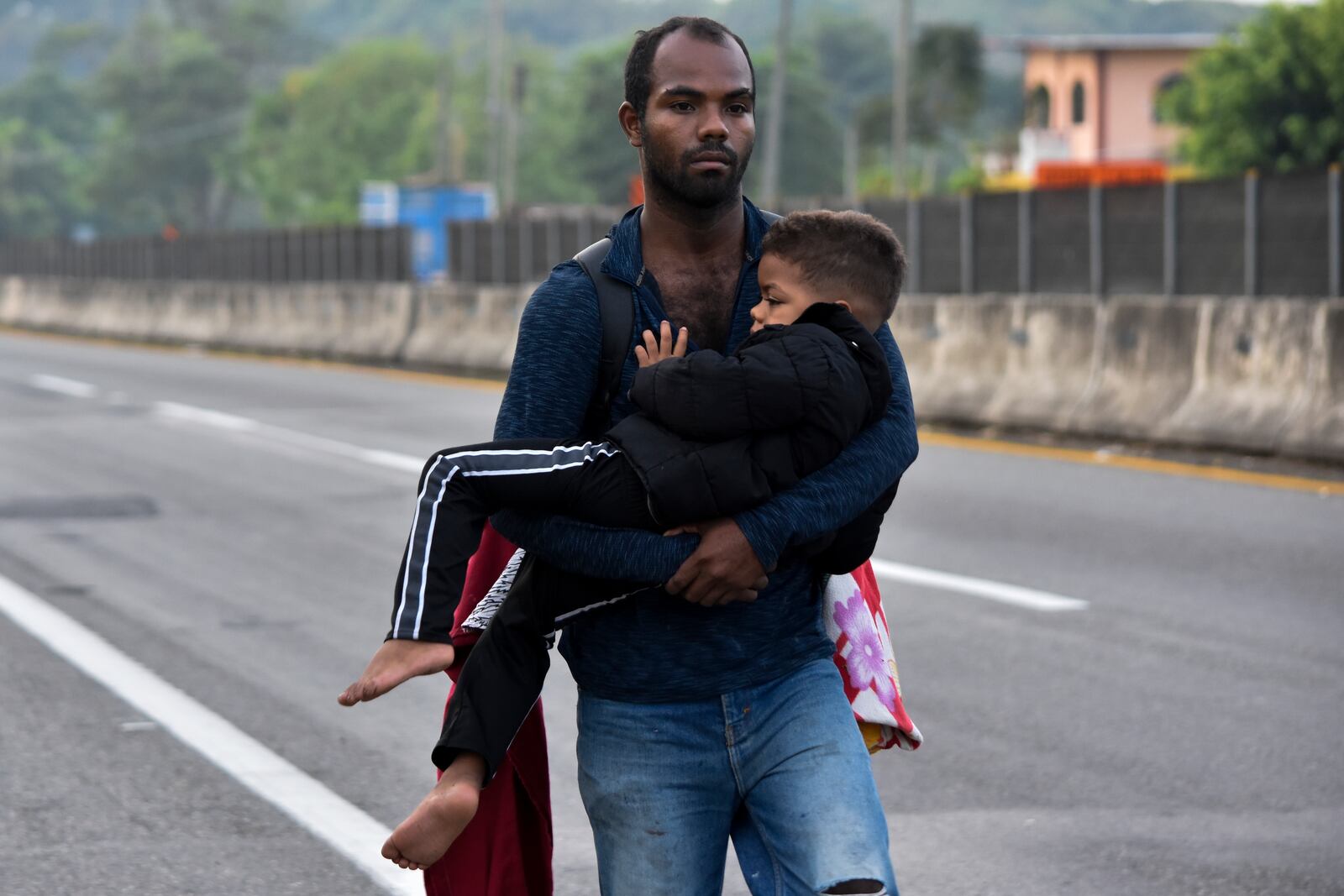 A migrant carries a child through Tapachula, Chiapas state, Mexico, Thursday, Jan. 2, 2025, as part of a caravan of migrants trying to reach the U.S. border. (AP Photo/Edgar H. Clemente)