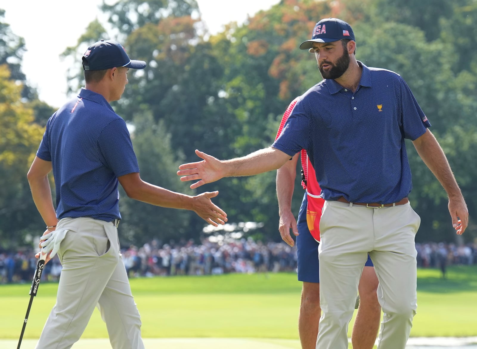 United States team member Scottie Scheffler, right, shakes hands with partner Collin Morikawa after making a putt on the 15th hole during the third round at the Presidents Cup golf tournament at Royal Montreal Golf Club in Montreal Saturday, Sept. 28, 2024. (Nathan Denette/The Canadian Press via AP)