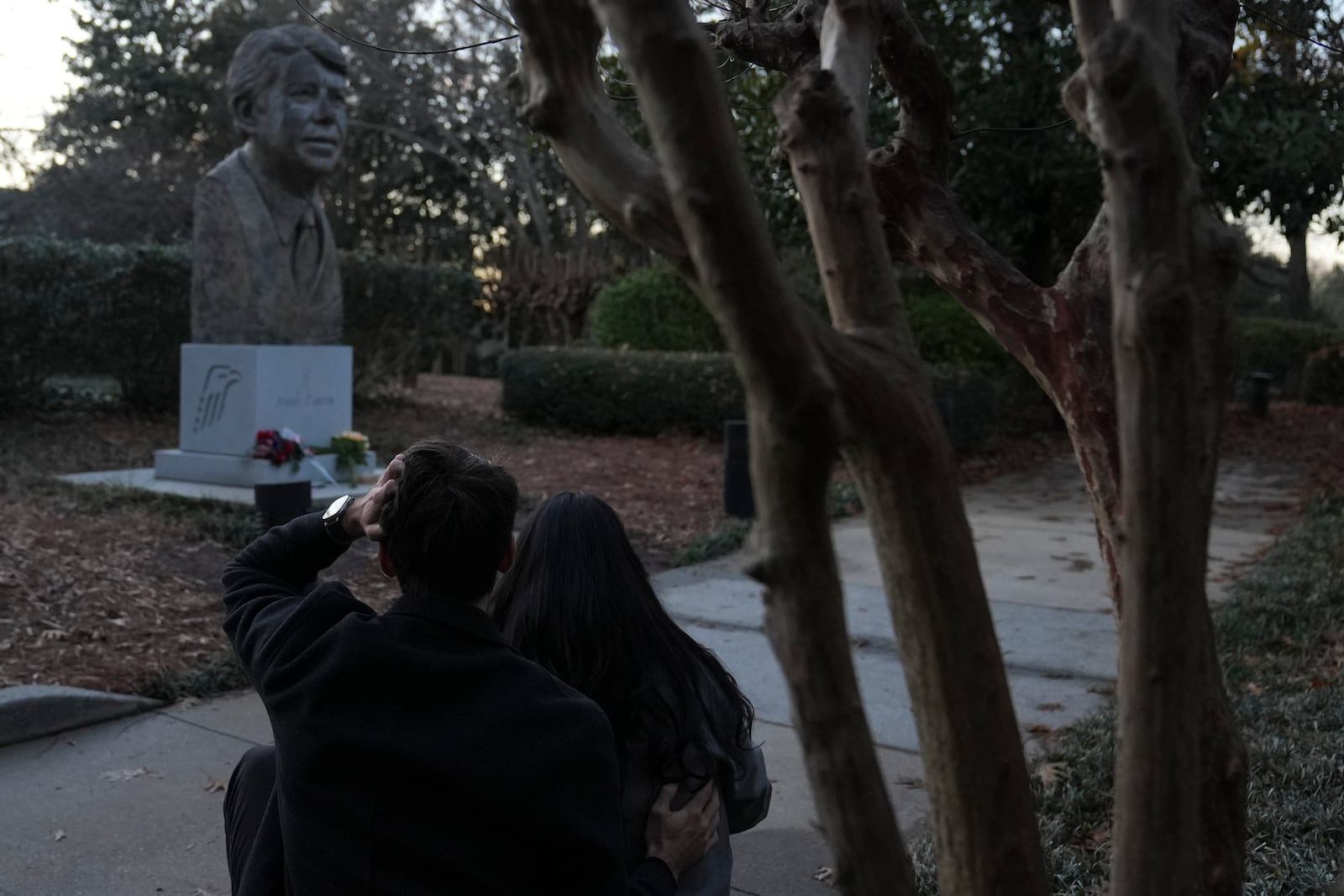 A couple sits near a bust of former President Jimmy Carter at the Jimmy Carter Presidential Library and Museum on Sunday, Dec. 29, 2024, in Atlanta. (AP Photo/Brynn Anderson)