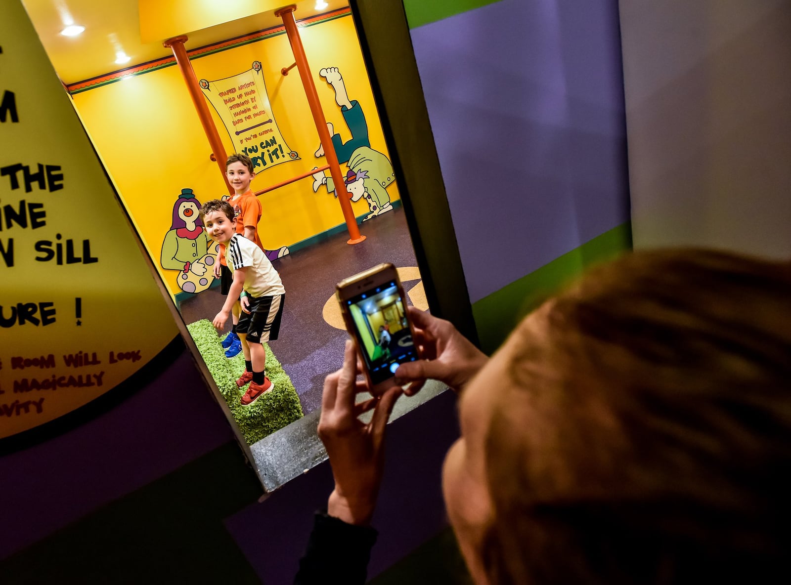 Laura Shiffman, from Kansas City, takes a photo of her sons, Noah, 4, and Aiden, 7, in the tilted room inside the A-Maze-N Funhouse at EnterTRAINment Junction Thursday, June 11, 2020 in West Chester Township. EnterTRAINment Junction has reopened after being closed for 85 days due to the coronavirus pandemic. The facility features the world’s largest indoor train display with nearly two miles of track, the A-Maze-N Funhouse, a children’s play area and more. NICK GRAHAM / STAFF