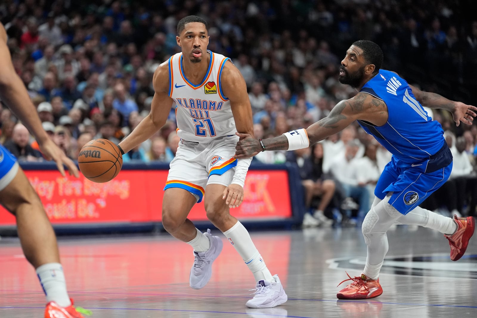 Oklahoma City Thunder guard Aaron Wiggins (21) is grabbed by Dallas Mavericks guard Kyrie Irving (11) during the first half of an NBA basketball game Friday, Jan. 17, 2025, in Dallas. (AP Photo/LM Otero)