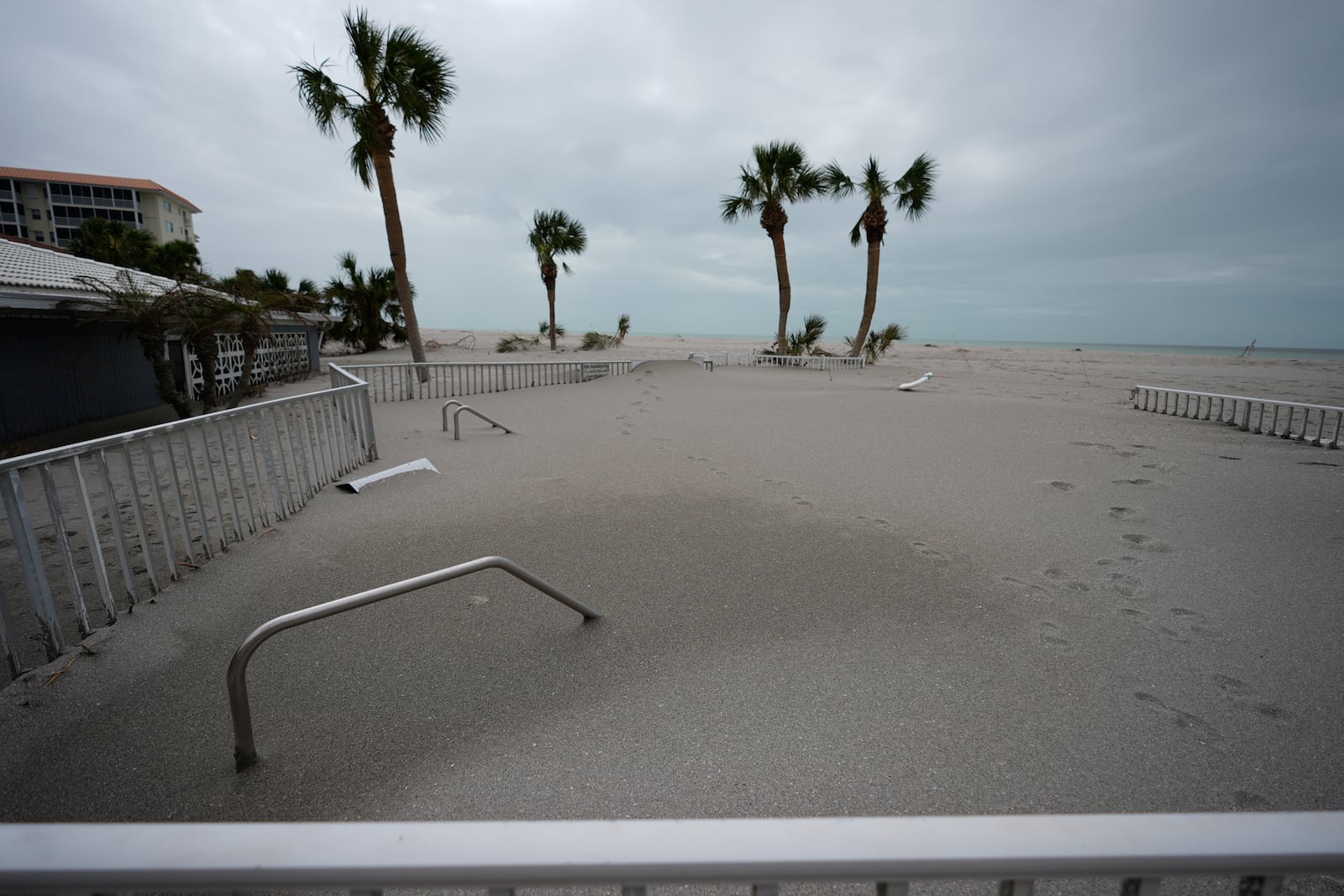 Only handrails are visible after a beachfront swimming pool was inundated with sand displaced by Hurricane Milton, at Sea Villas condominiums in Venice, Fla., Friday, Oct. 11, 2024. (AP Photo/Rebecca Blackwell)