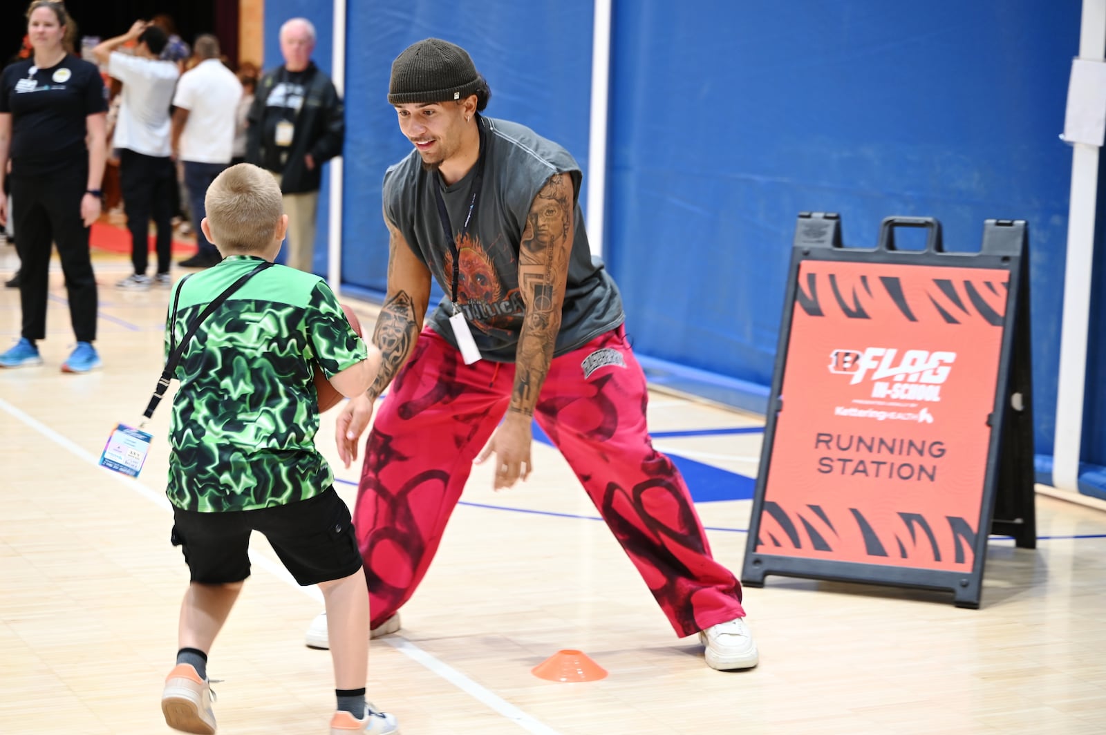 Just a Pair of Shoes, a nonprofit organization that distributes free high-end shoes distributed 120 pairs to students at Highland Elementary School in the Hamilton City School District. The event was sponsored by Kettering Health and the Cincinnati Bengals. After receiving the shoes, the students put them on and tried them out. Pictured is Bengals running back Chase Brown defending a student during a football running drill. MICHAEL D. PITMAN/STAFF