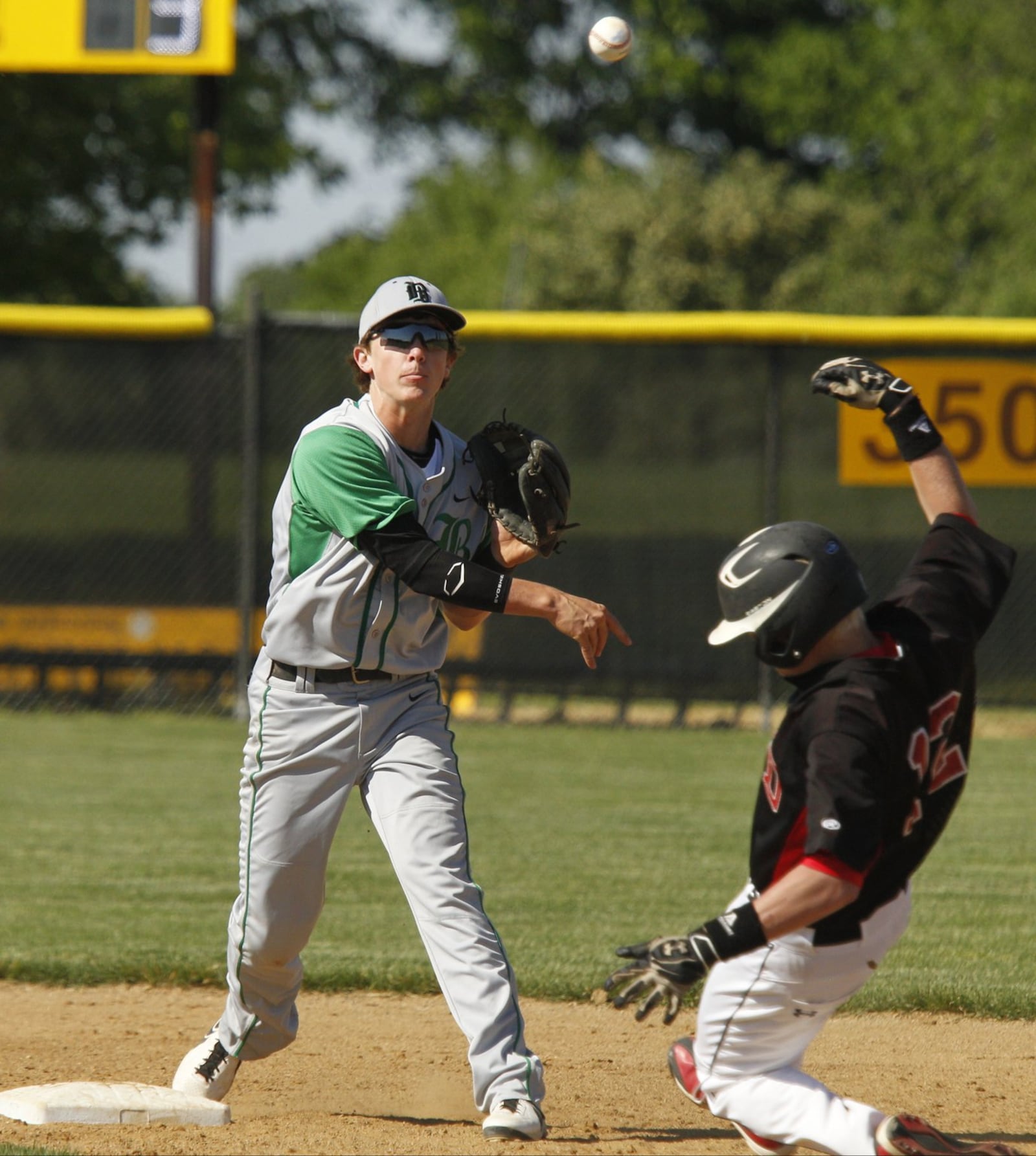 Badin’s Alex Holderbach (14) throws to first base for the double play as Triad’s Marshall O’Brien (12) slides in to second base during a Division III district final at Springfield Kenton Ridge on May 24, 2013. Holderbach’s Rams won 9-7. COX MEDIA FILE PHOTO