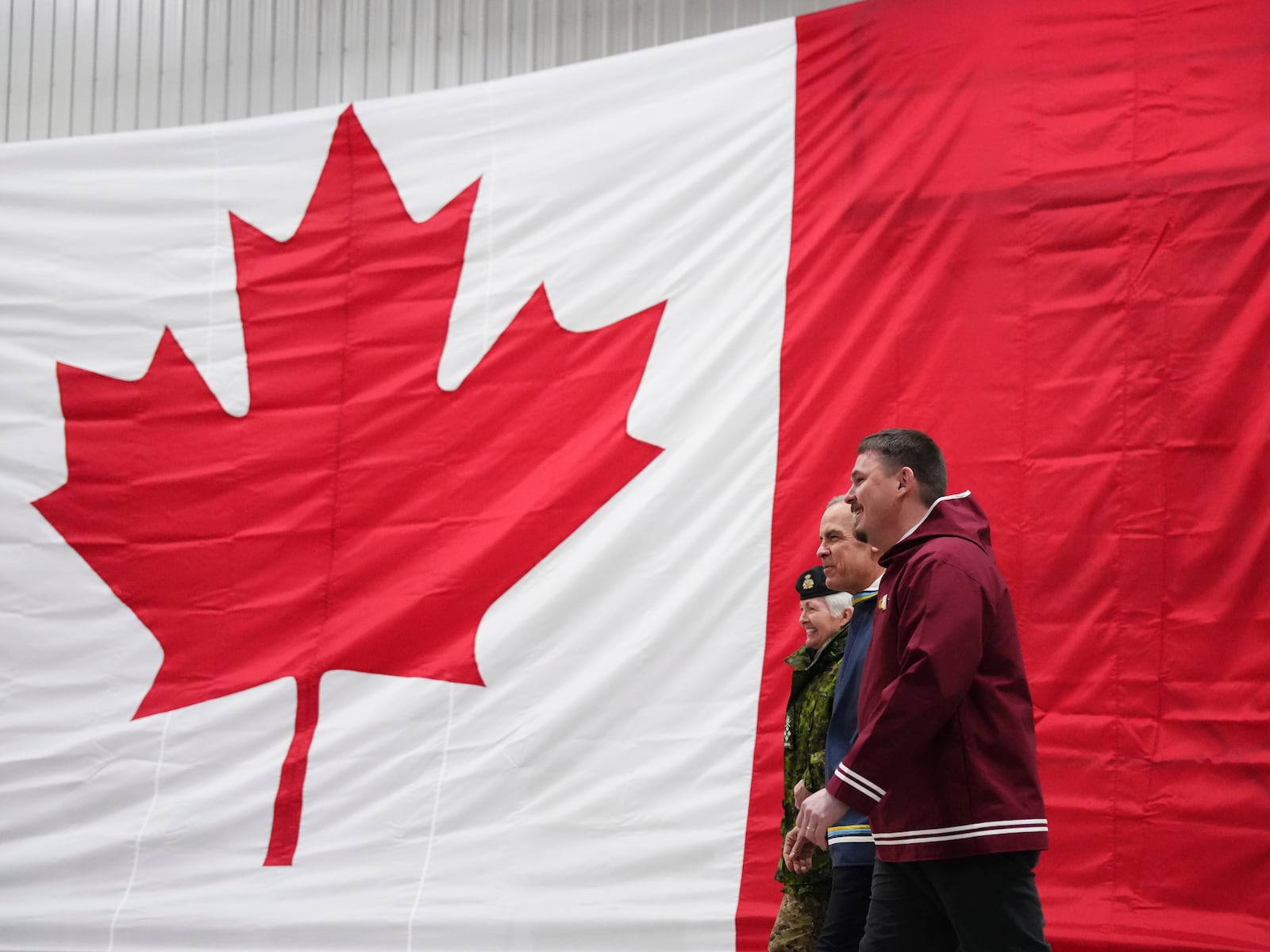 Canada Chief of Defence Staff Gen. Jennie Carignan, left to right, Prime Minister Mark Carney and Nunavut Premier P.J. Akeeagok arrive to make an announcement at a Canadian Armed Forces forward-operating location in Iqaluit, Nunavut, on Tuesday, March 18, 2025. (Sean Kilpatrick/The Canadian Press via AP)