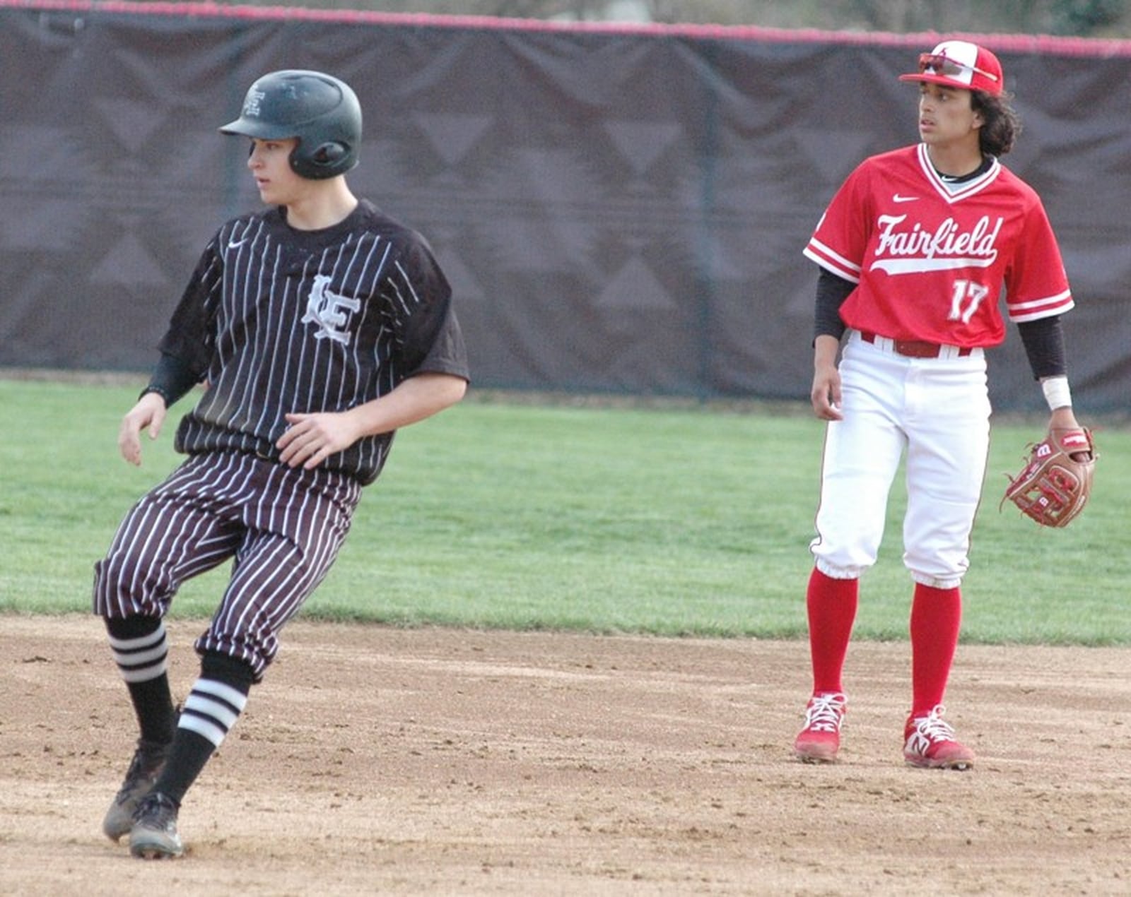 Lakota East’s Grayson Hamilton rounds second base while looking at the outfield with Fairfield’s Ricky Berrios on April 3 during a Greater Miami Conference baseball game at Joe Nuxhall Field in Fairfield. East won 2-1. RICK CASSANO/STAFF