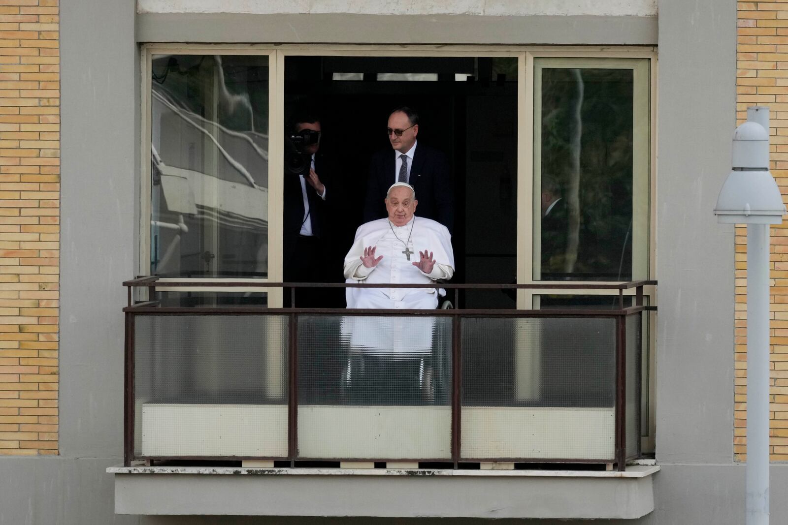 Pope Francis waves as he appears at a window of the Agostino Gemelli Polyclinic in Rome, Sunday, March 23, 2025, where he has been treated for bronchitis and bilateral pneumonia since Feb. 14. (AP Photo/Andrew Medichini)