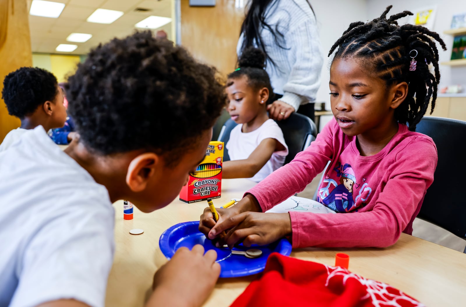 Saniah Lewis, 7, right, helps Kalis Goins, 8, with an eclipse craft  as kids from Booker T. Washington Center and Boys and Girls Clubs of Hamilton learned about the upcoming total solar eclipse Thursday, April 4, 2024 at Booker T. Washington Community Center in Hamilton. The kids made homemade eclipse viewers and a diorama of the eclipse. NICK GRAHAM/STAFF