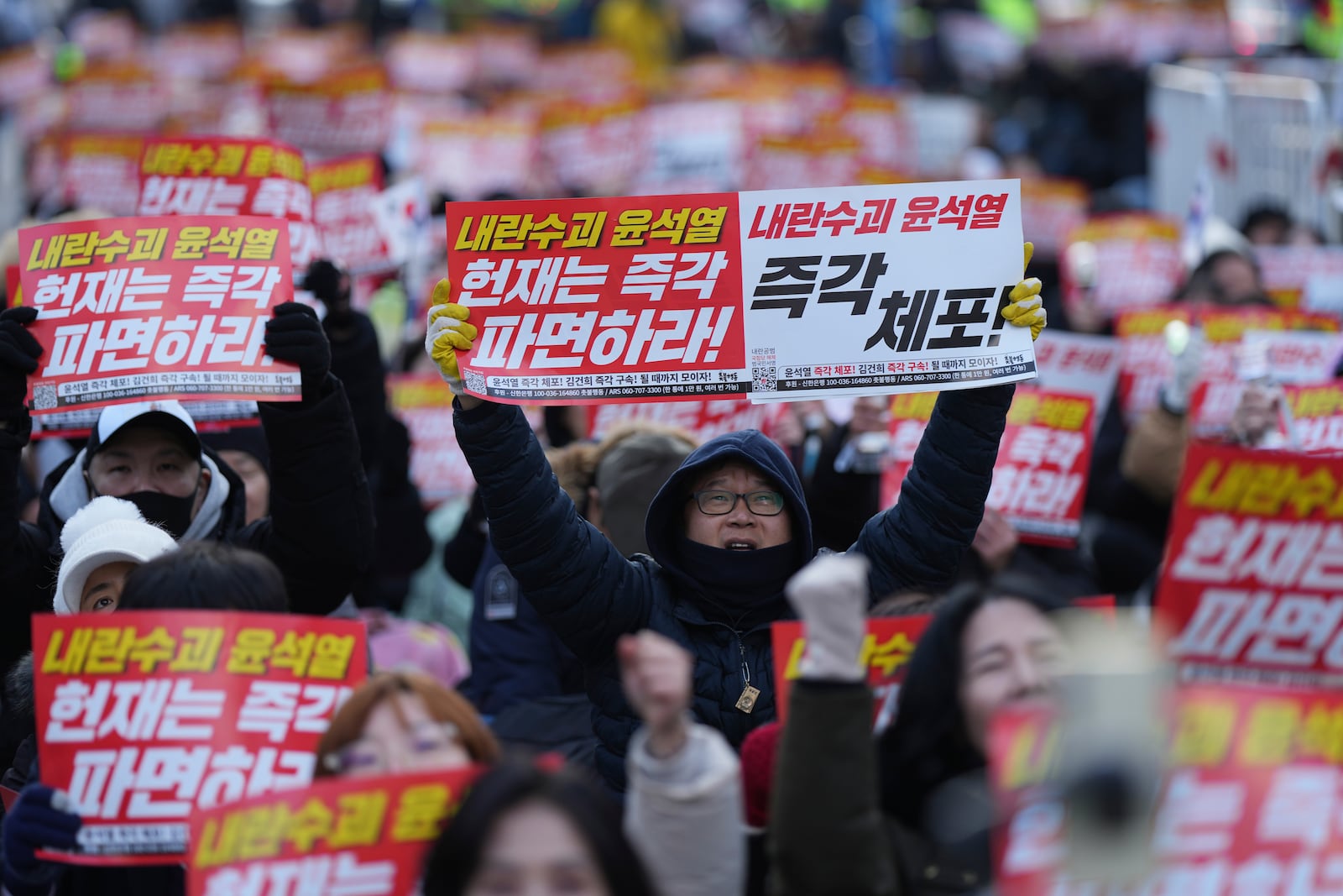 Participants shout slogans during a rally calling on the Constitutional Court to dismiss the President Yoon Suk Yeol, in Seoul, South Korea, Sunday, Dec. 15, 2024. The signs read "Immediately arrest." (AP Photo/Lee Jin-man)