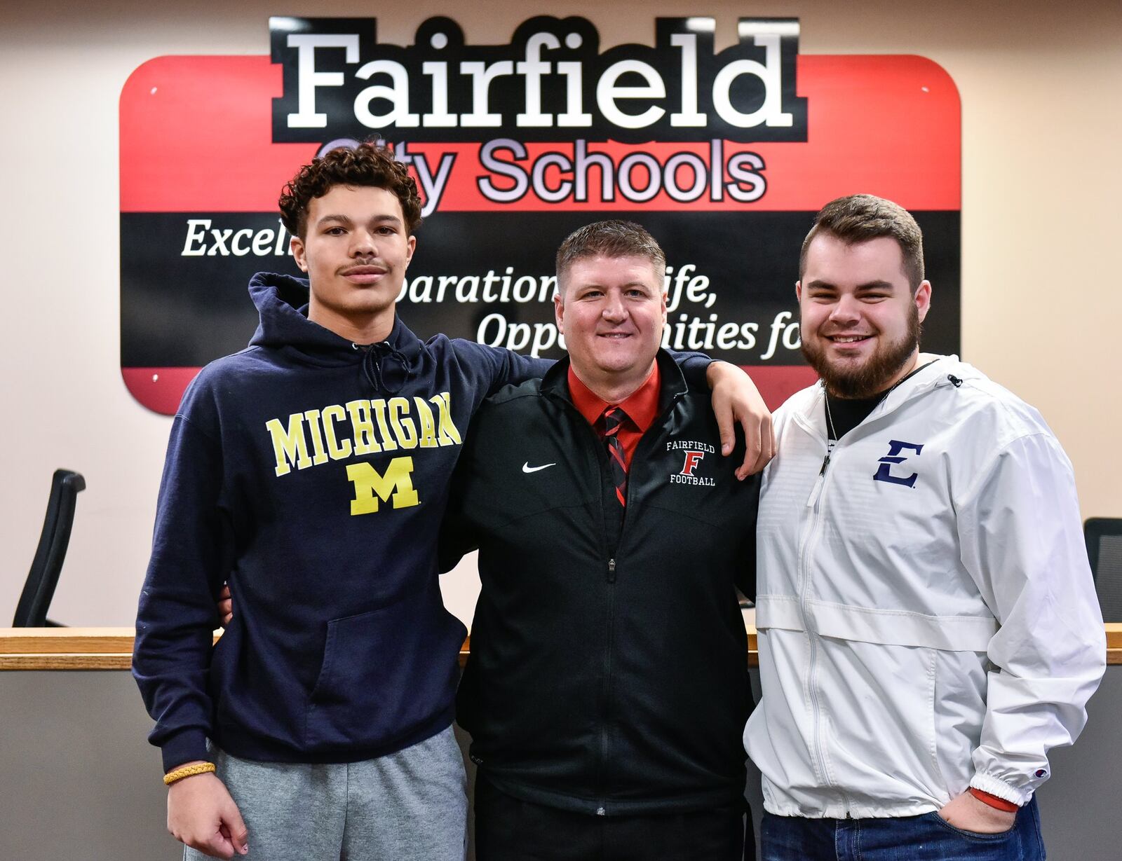 Fairfield seniors Erick All (left) and Jacob Hensley (right) stand with football coach Jason Krause during an early National Signing Day ceremony Wednesday morning at Fairfield High School. NICK GRAHAM/STAFF