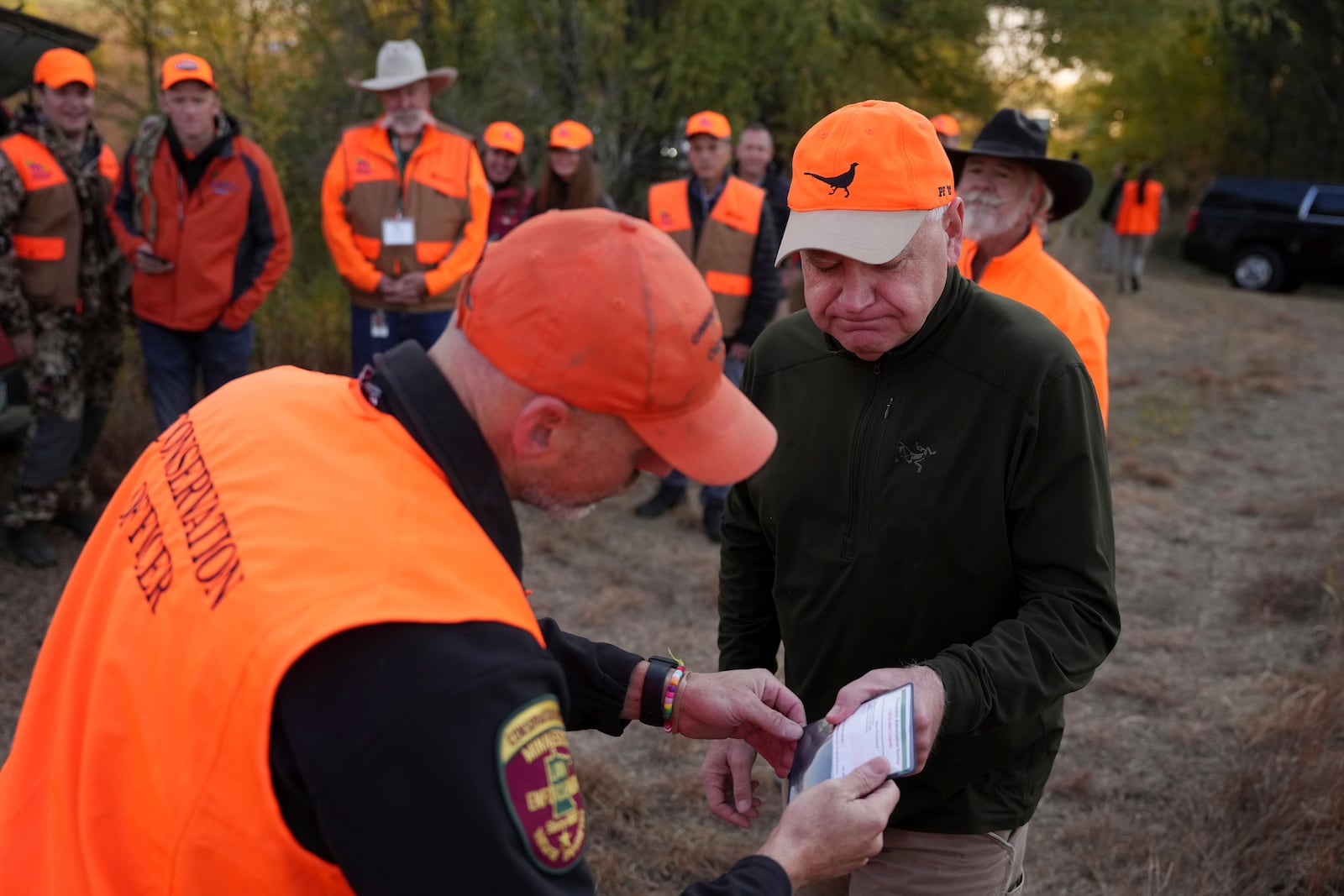 Minnesota Governor and Democratic Vice Presidential candidate Tim Walz gets his hunting license ceremoniously inspected before heading out for the annual Minnesota Governor's Pheasant Hunting Opener, Saturday, Oct. 12, 2024, near Sleepy Eye, Minn. (Anthony Souffle/Star Tribune via AP)