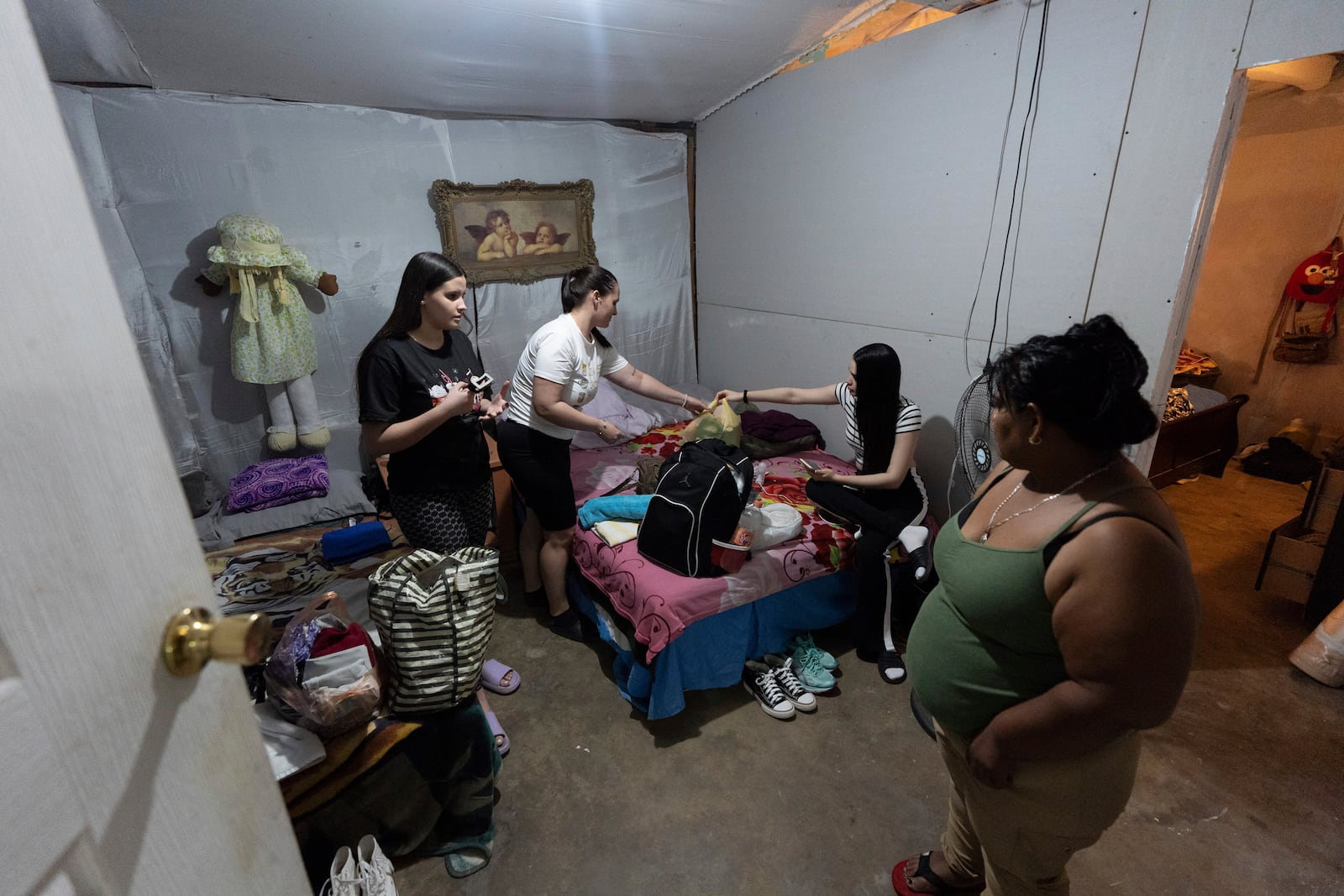 Martha Rosales, right, looks on as Cuban migrants pack their things after receiving an appointment to apply for asylum in the United States through the CBP One app Wednesday, Aug. 28, 2024, in Tijuana, Mexico. (AP Photo/Gregory Bull)