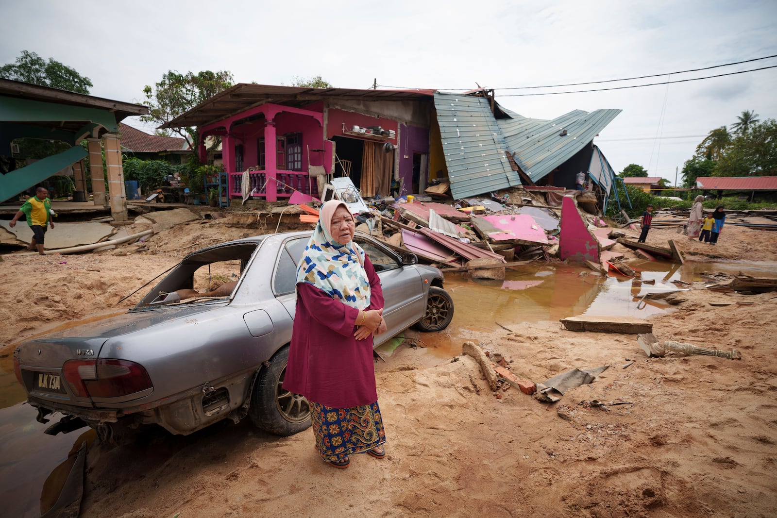 Asmah Ibrahim, 60 years old resident reacts as she stands outside of her house damaged by flood in Tumpat, on the outskirts of Kota Bahru, Malaysia, Tuesday, Dec. 3, 2024. (AP Photo/Vincent Thian)