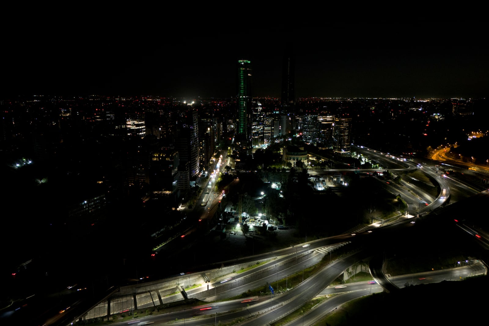 Cars zip past dark buildings during a power outage in Santiago, Chile, Tuesday, Feb. 25, 2025. (AP Photo/Matias Basualdo)