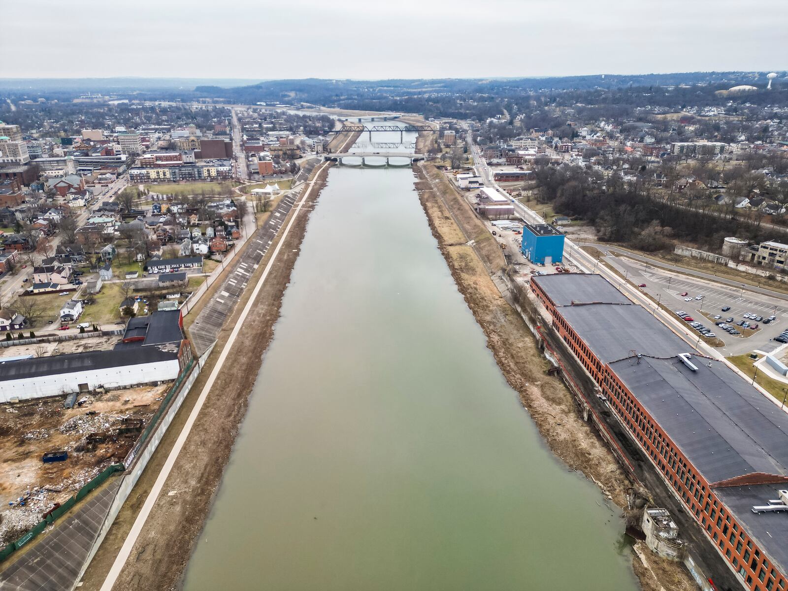 Dublin-based Crawford Hoying plans to redevelop the 17.7-acre Cohen Recycling plant, left, along the Great Miami River in Hamilton into a $150 million-minimum mixed-used development that features retail, housing and a hotel. The location is across the river from Spooky Nook Sports Champion Mill sports complex, hotel and convention center, right. NICK GRAHAM/STAFF