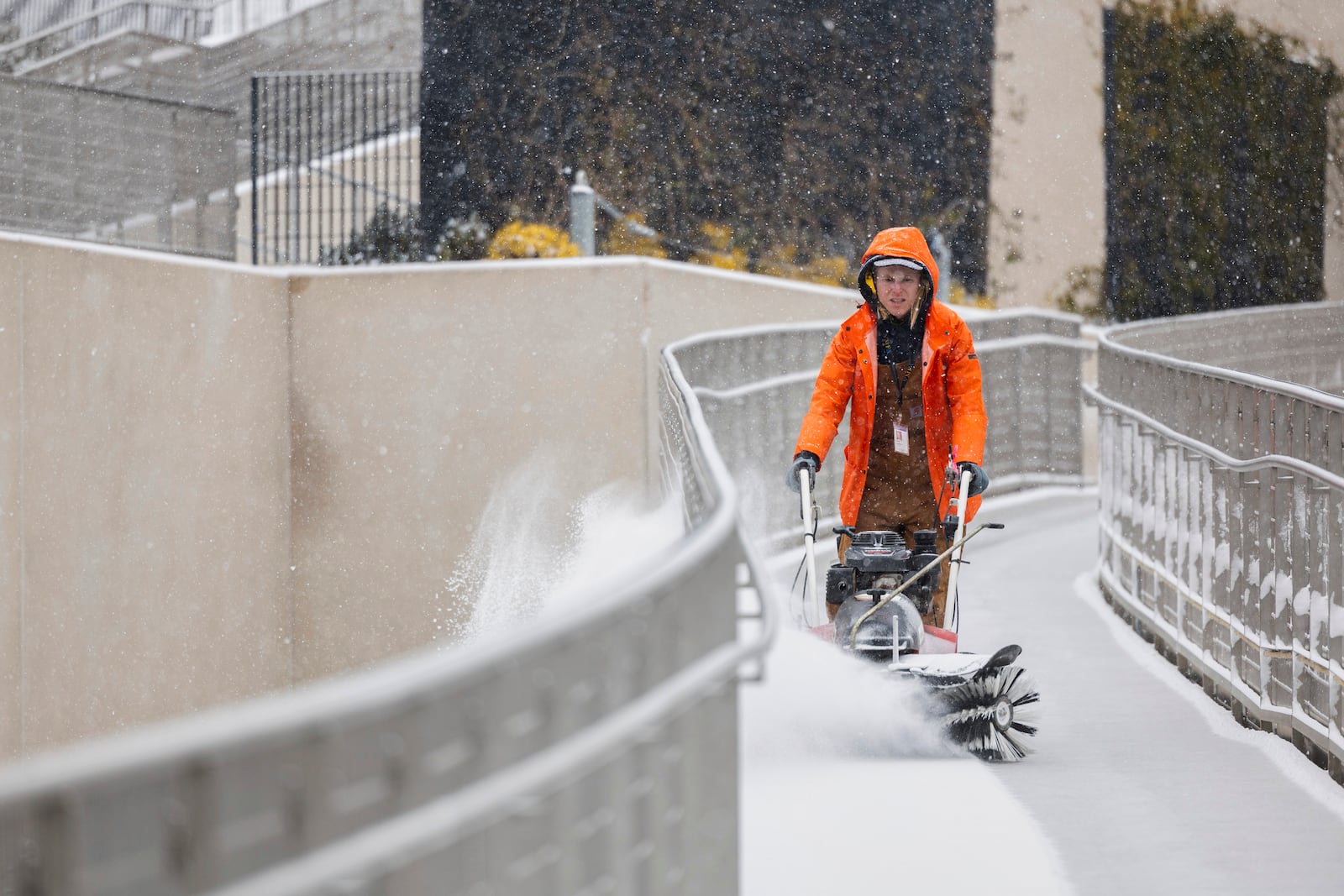 A worker clears snow from the pathway between the parking deck and the VMFA, Wednesday, Feb. 19, 2025, in Richmond, Va. (Margo Wagner/Richmond Times-Dispatch via AP)