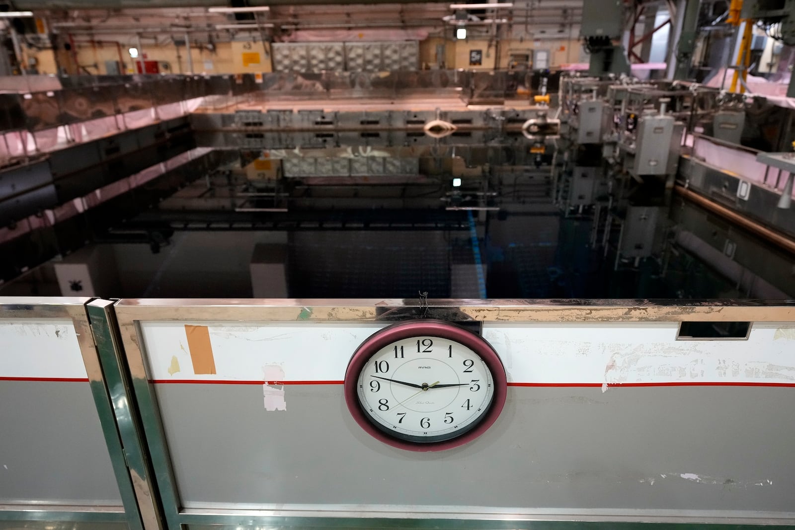 A cooling pool for nuclear fuel units and a clock that apparently had stopped when the time earthquake and tsunami struck the plant on March 11, 2011, is seen at the Fukushima Daiichi nuclear power plant, run by TEPCO, in Okuma town, northeastern Japan, on Monday Feb. 20, 2025. (AP Photo/Eugene Hoshiko)