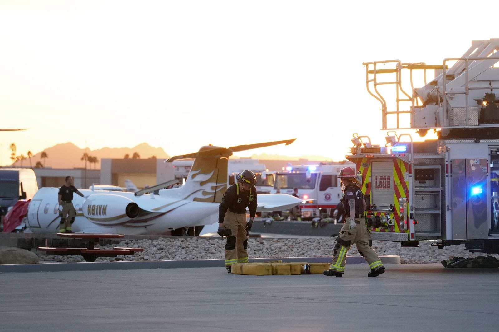 Firefighters work around the site of a crashed Learjet at Scottsdale Airport after it collided with a parked plane Monday, Feb. 10, 2025, in Scottsdale, Ariz. (AP Photo/Ross D. Franklin)