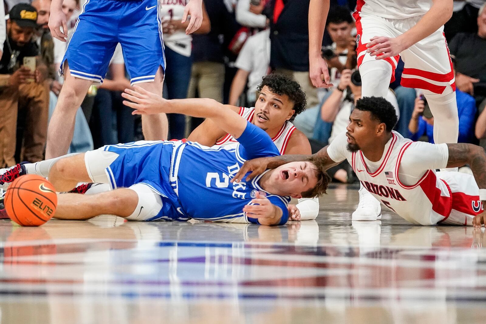 Arizona forward Trey Townsend, left rear, and guard KJ Lewis, right, battle for a loose ball with Duke guard Cooper Flagg (2) during the second half of an NCAA college basketball game Friday, Nov. 22, 2024, in Tucson, Ariz. (AP Photo/Darryl Webb)