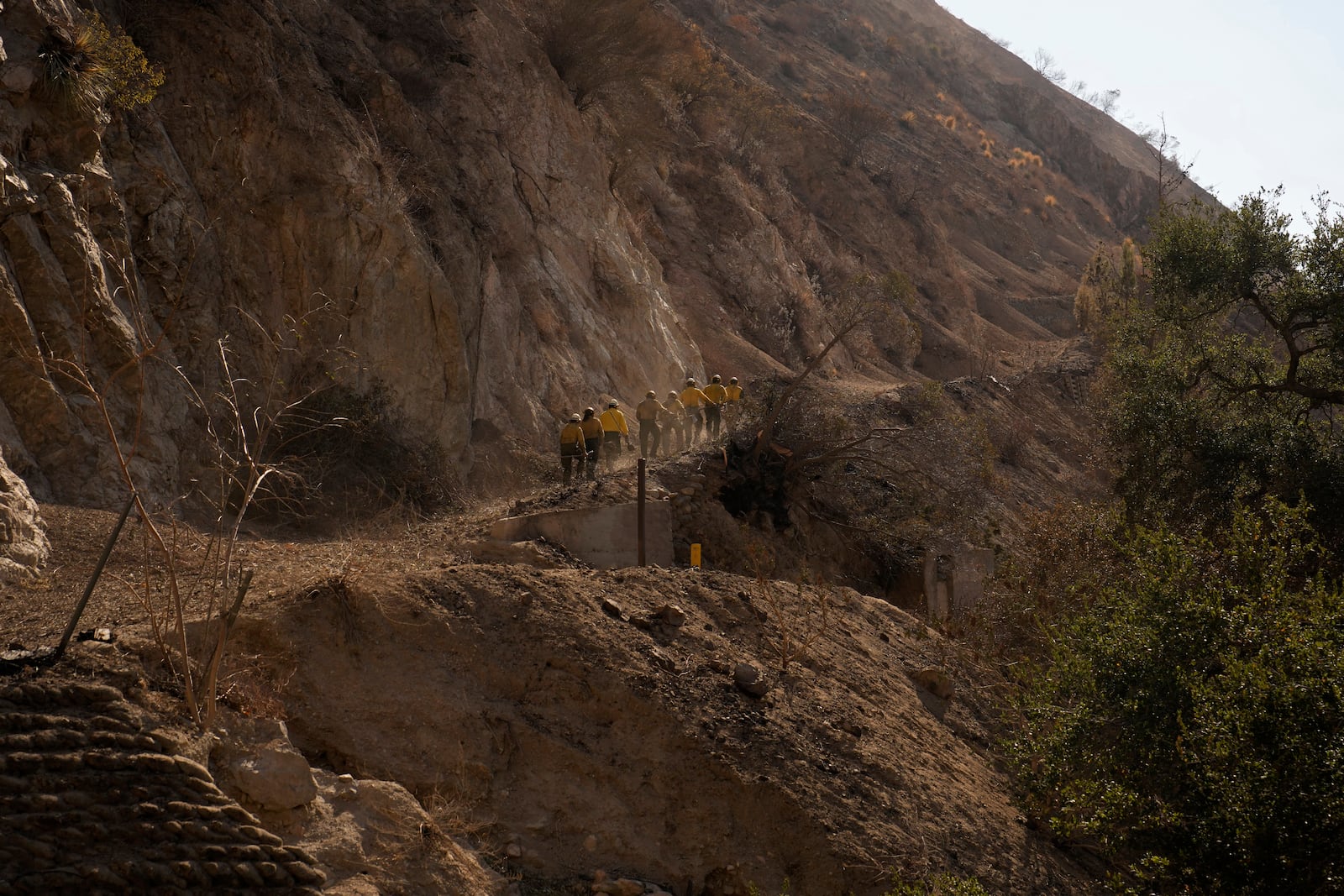 Members of Navajo Scouts firefighter crew hike up a road to clear debris from landslide across a road at the Eaton Fire, Friday, Jan. 17, 2025, in Altadena, Calif. (AP Photo/John Locher)