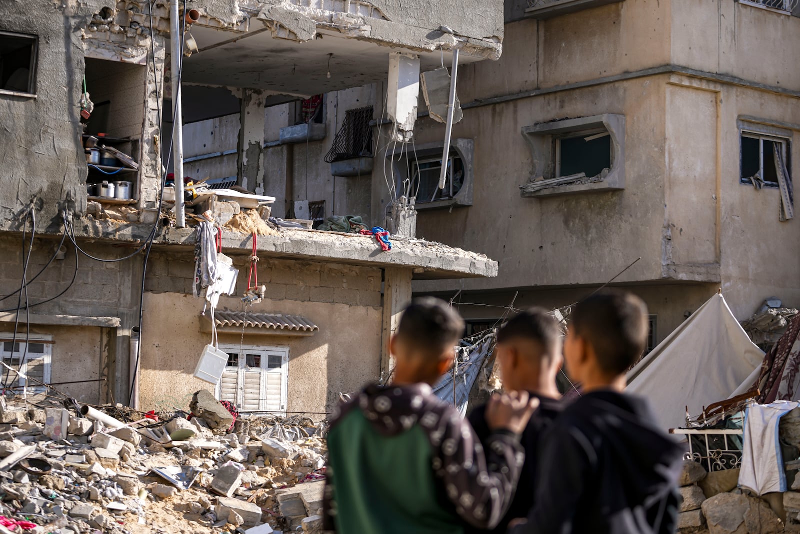 FILE - Palestinians look at a damaged residential building following an overnight Israeli strike in Deir al-Balah, Gaza Strip, Wednesday, Jan. 8, 2025. (AP Photo/Abdel Kareem Hana, File)