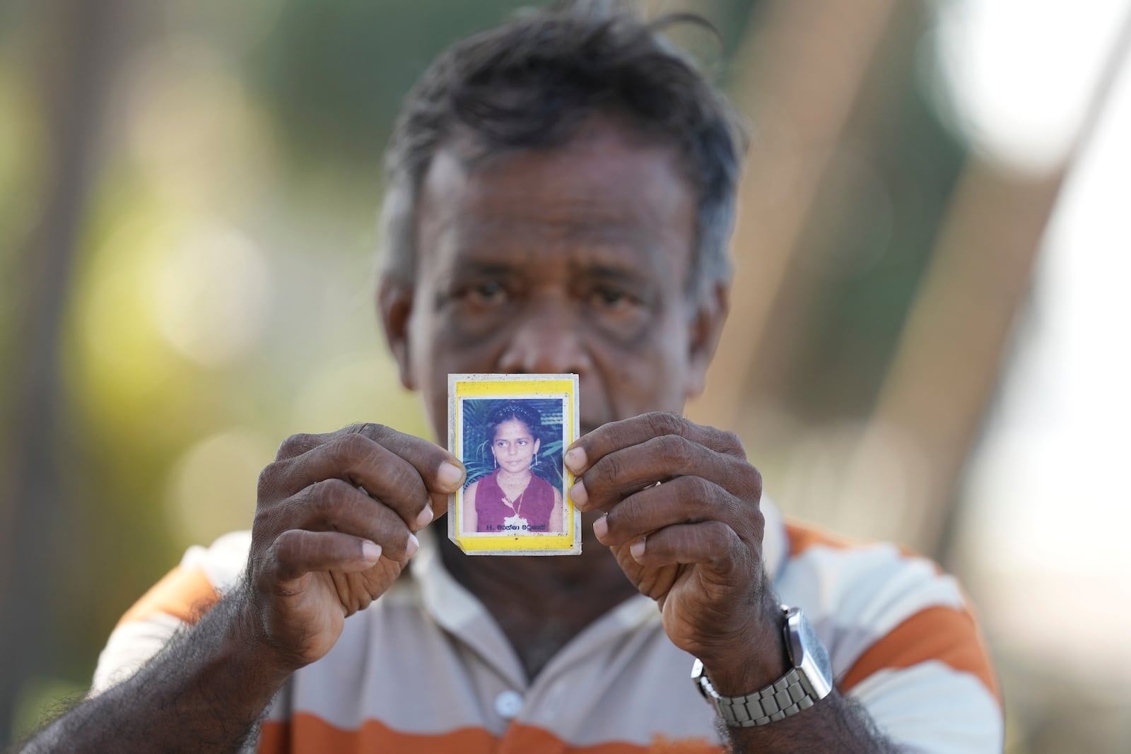 Dayaratne Halambage shows a portrait of his daughter who died during the 2004 Indian Ocean tsunami at a memorial of the 20th anniversary of the calamity in Peraliya, Sri Lanka, Thursday, Dec. 26, 2024. (AP Photo/Eranga Jayawardena)