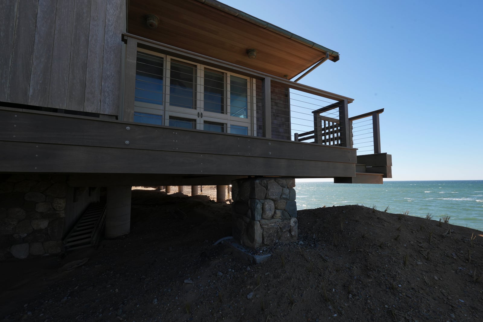 A home sits atop of a sandy bluff overlooking a beach in Wellfleet, Mass., Monday, Jan. 27, 2025. (AP Photo/Andre Muggiati)