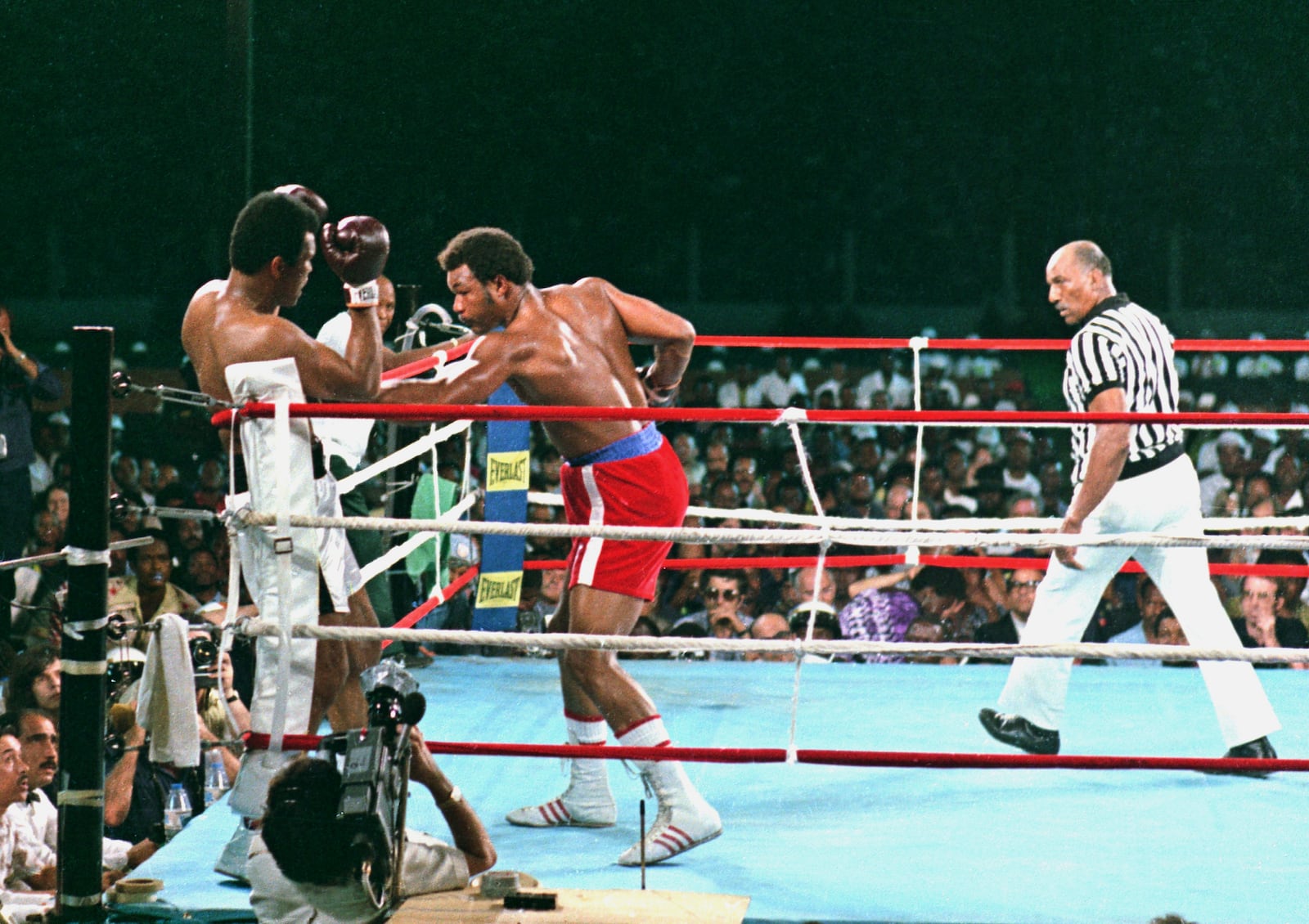 FILE - George Foreman, center, lands a body punch to Muhammad Ali during fight action in Zaire, Africa, Oct. 30, 1974. Referee Zack Clayton is at right.(AP Photo, File)