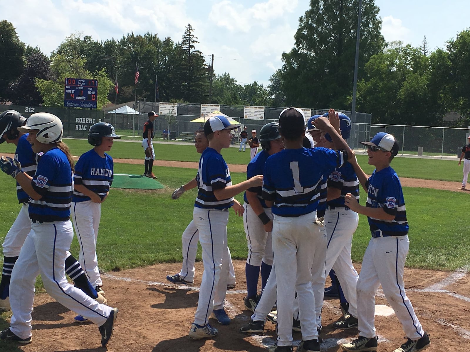 Hamilton West Side’s Lake Cundiff is congratulated by teammate Braedyn Moore (1) and others after hitting a first-inning home run Tuesday at Ford Park’s Robert S. Hoag Field in Maumee. West Side defeated Mt. Vernon 12-3 in the Ohio Little League 12-year-old baseball tournament. RICK CASSANO/STAFF