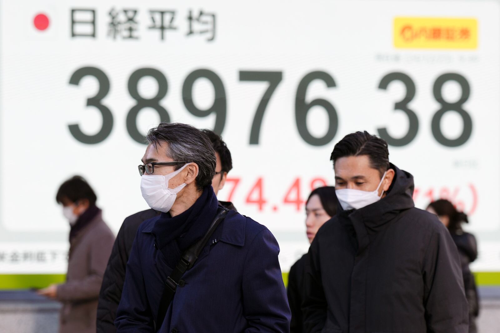 People walk in front of an electronic stock board showing Japan's Nikkei index at a securities firm Monday, Dec. 23, 2024, in Tokyo. (AP Photo/Eugene Hoshiko)