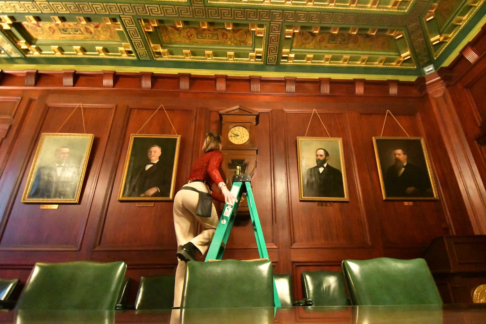 Bethany Gill climbs a ladder to wind a clock in a Pennsylvania Senate hearing chamber, Dec. 13, 2024, in Harrisburg, Pa. It's one of 273 clocks in Pennsylvania's ornate state Capitol complex buildings that must be wound by hand. (AP Photo/Marc Levy)