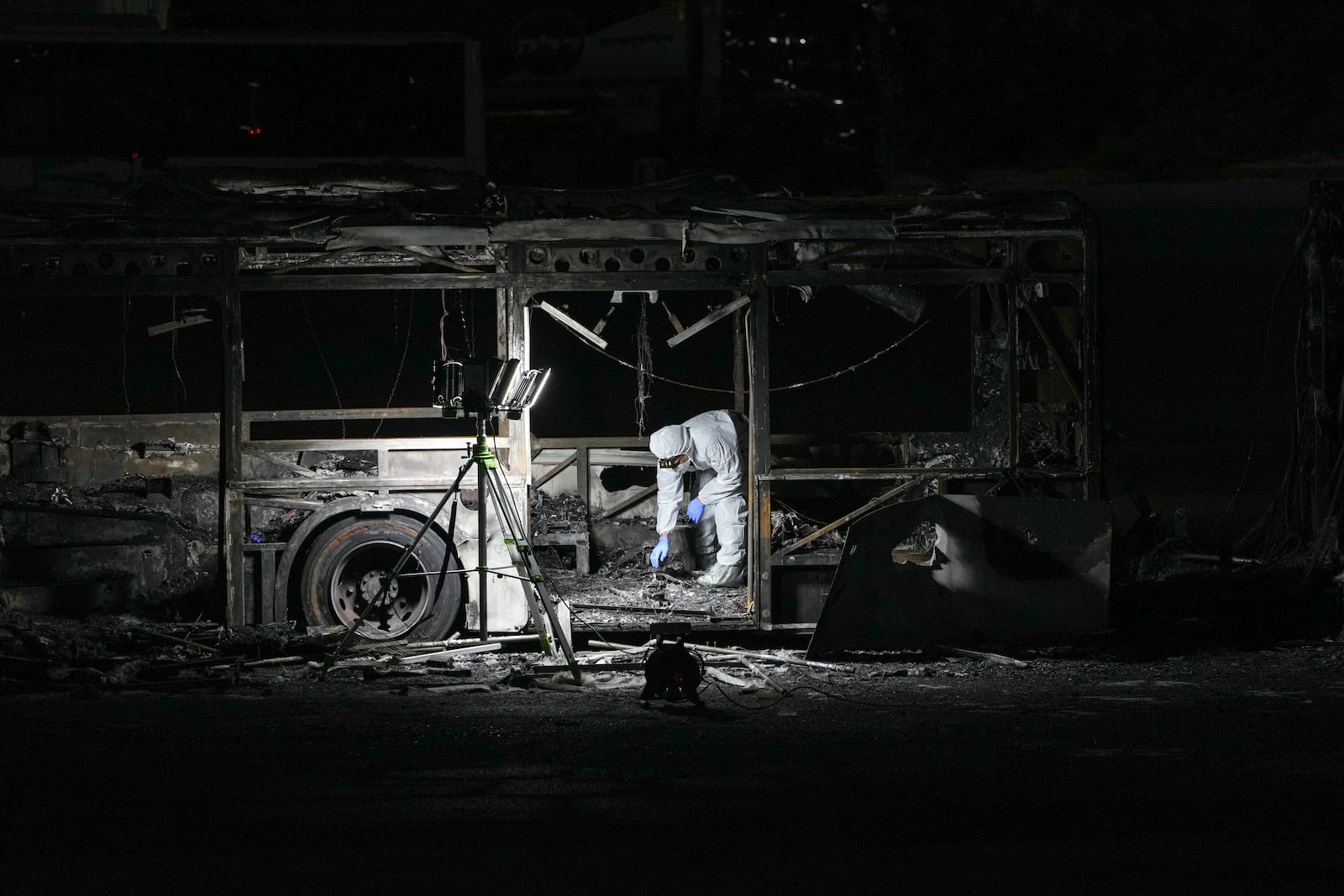 An Israeli police officer inspects the scene of one of a series of bus explosions in what authorities said appeared to be a militant attack in Bat Yam, central Israel, Thursday, Feb. 20, 2025. (AP Photo/Ohad Zwigenberg)