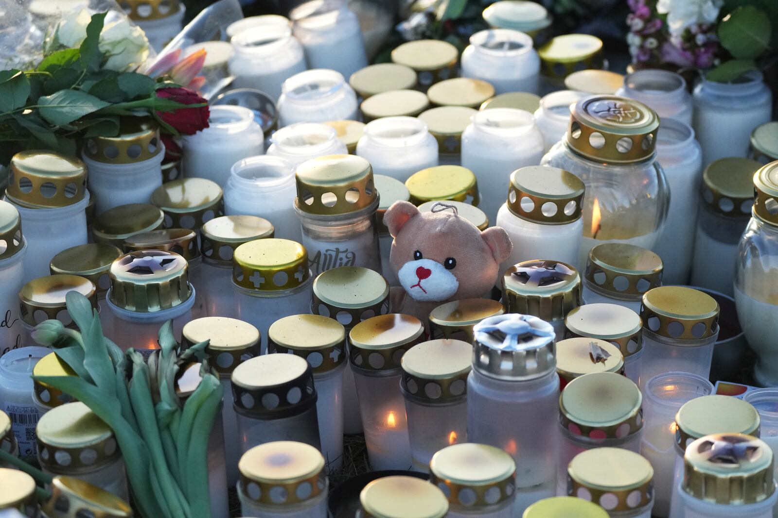 A teddy bear, flowers and candles are placed at a makeshift memorial near the scene of a shooting at an adult education center on the outskirts of Orebro, Sweden, Thursday, Feb. 6, 2025. (AP Photo/Sergei Grits)