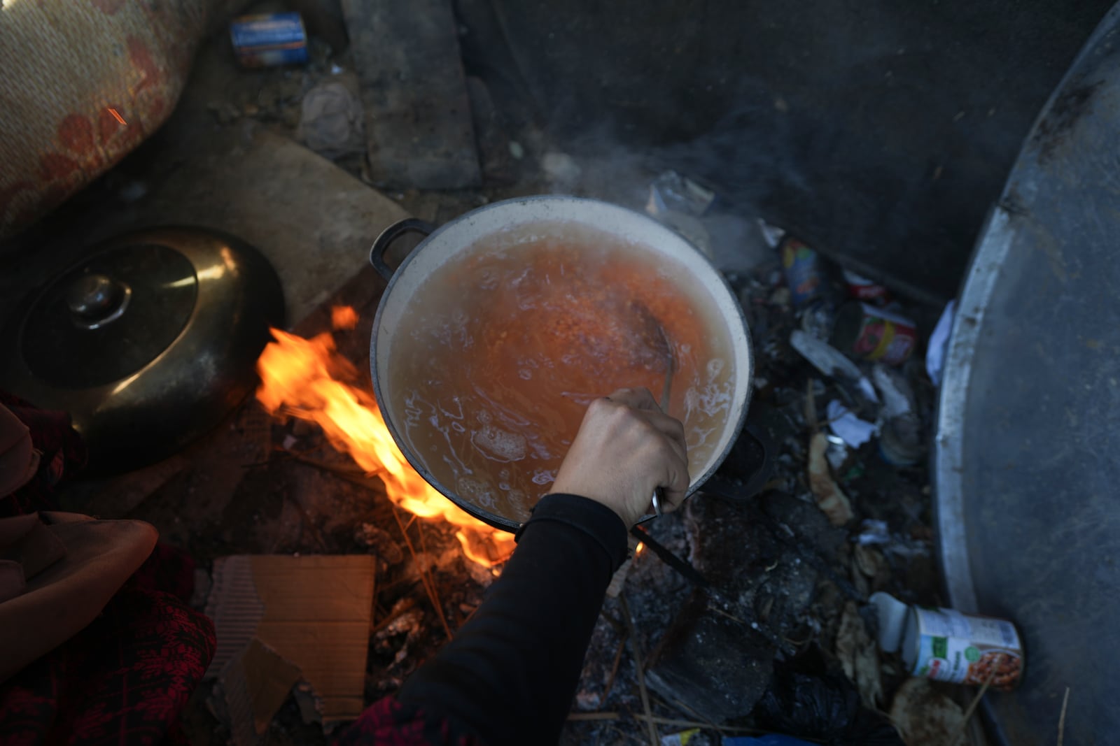 Yasmin Eid cooks a pot of lentils for her four daughters at their tent in a refugee camp in Deir al-Balah, Gaza Strip, Tuesday Nov. 19, 2024. (AP Photo/Abdel Kareem Hana)