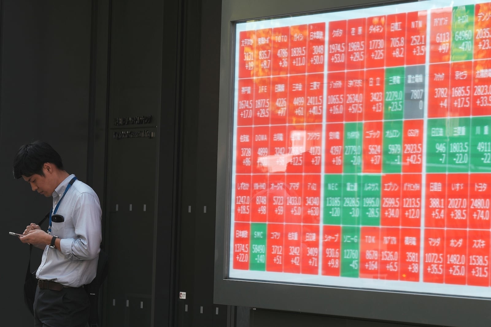 FILE - A person stands near an electronic stock board showing Japan's Nikkei index at a securities firm in Tokyo, on Sept. 18, 2024. (AP Photo/Eugene Hoshiko, File)