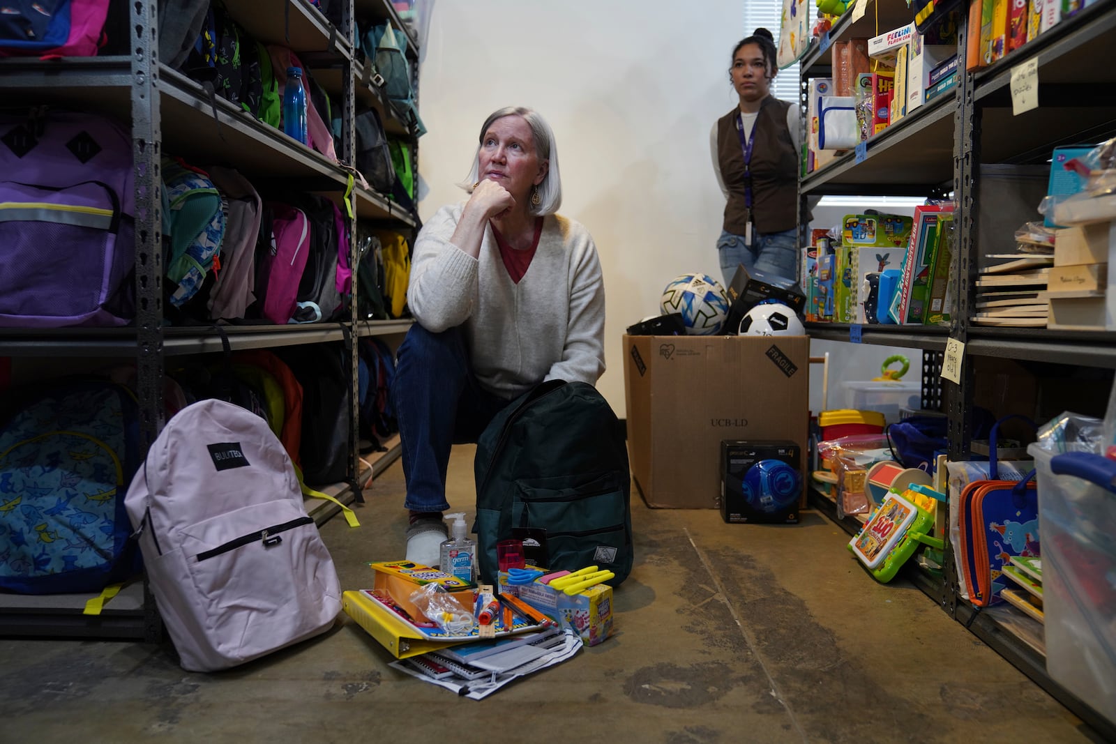 Beth Hickey, left, a volunteer with the Lutheran Social Services National Capital Area Resource Center, and Madi Davis, an employee with the resource center, look through school backpacks, in Alexandria, Va., Thursday, March 6, 2025. (AP Photo/Jessie Wardarski)