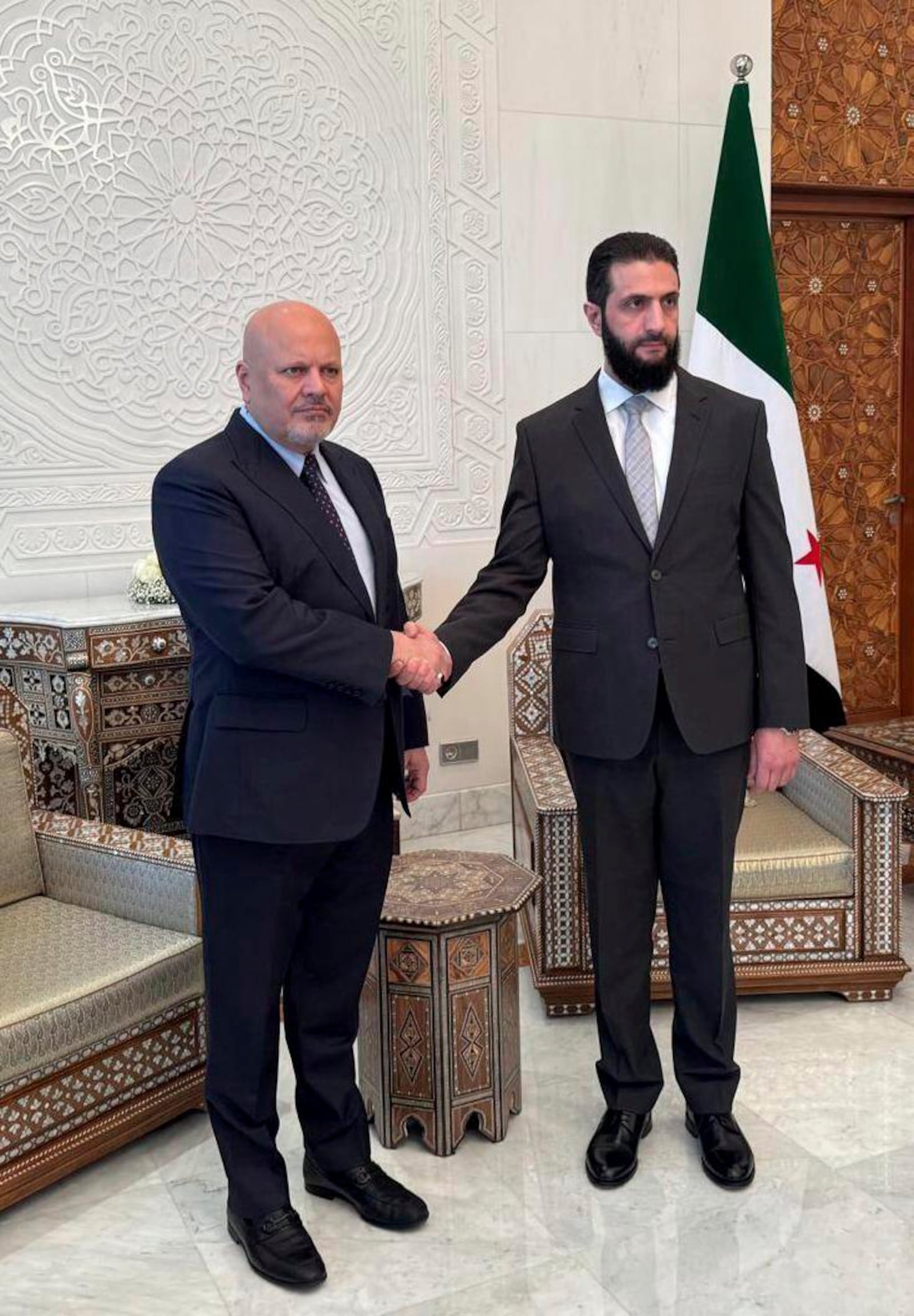 On this photo o released by the International Criminal Court, Karim Khan, Prosecutor of the International Criminal Court, left, and Syria's de facto leader Ahmad al-Sharaa shake hands during their meeting at the International Criminal Court, in The Hague, Netherlands, Friday, Jan. 17, 2025. (International Criminal Court via AP)