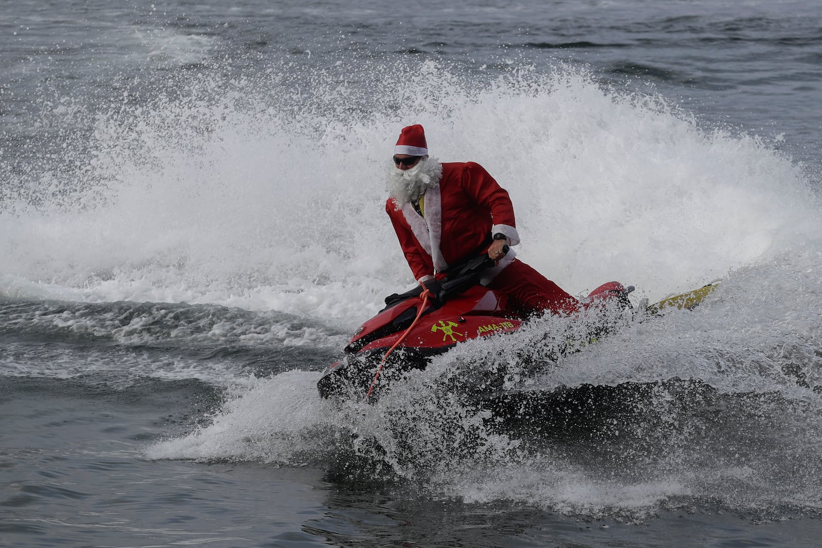 A firefighter dressed as Santa Claus drives a jet ski by Copacabana Beach in Rio de Janeiro, Tuesday, Dec. 17, 2024. (AP Photo/Bruna Prado)