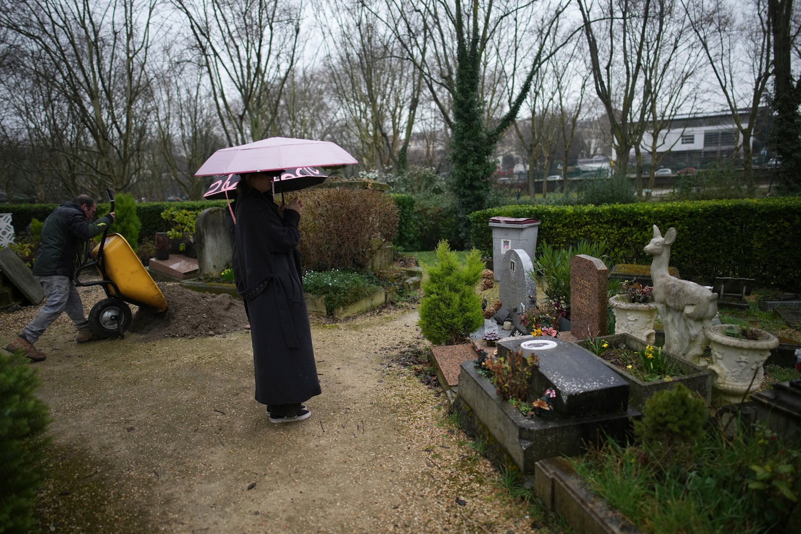 Tourists visit the dog cemetery while a worker prepares a tomb in Asnières-sur-Seine, outside Paris, Tuesday, Feb. 25, 2025. (AP Photo/Christophe Ena)