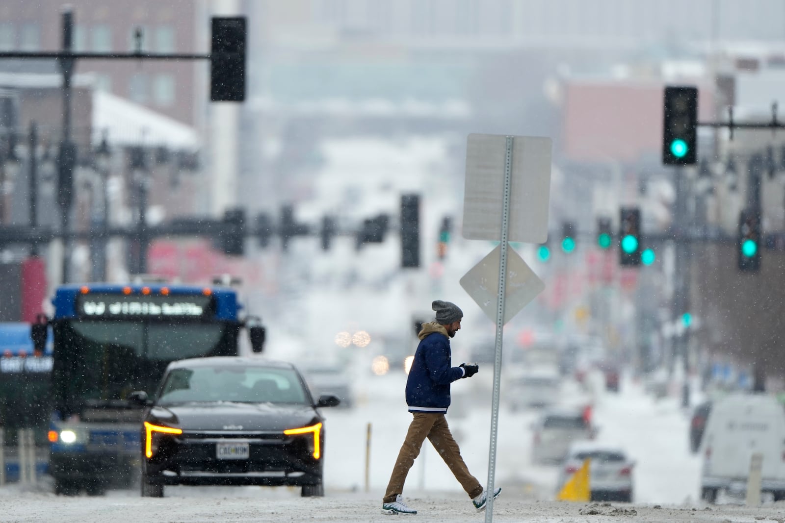 A pedestrian crosses a snowy street in downtown Kansas City, Mo., as a winter storm passed through the area Wednesday, Feb. 12, 2025. (AP Photo/Charlie Riedel)